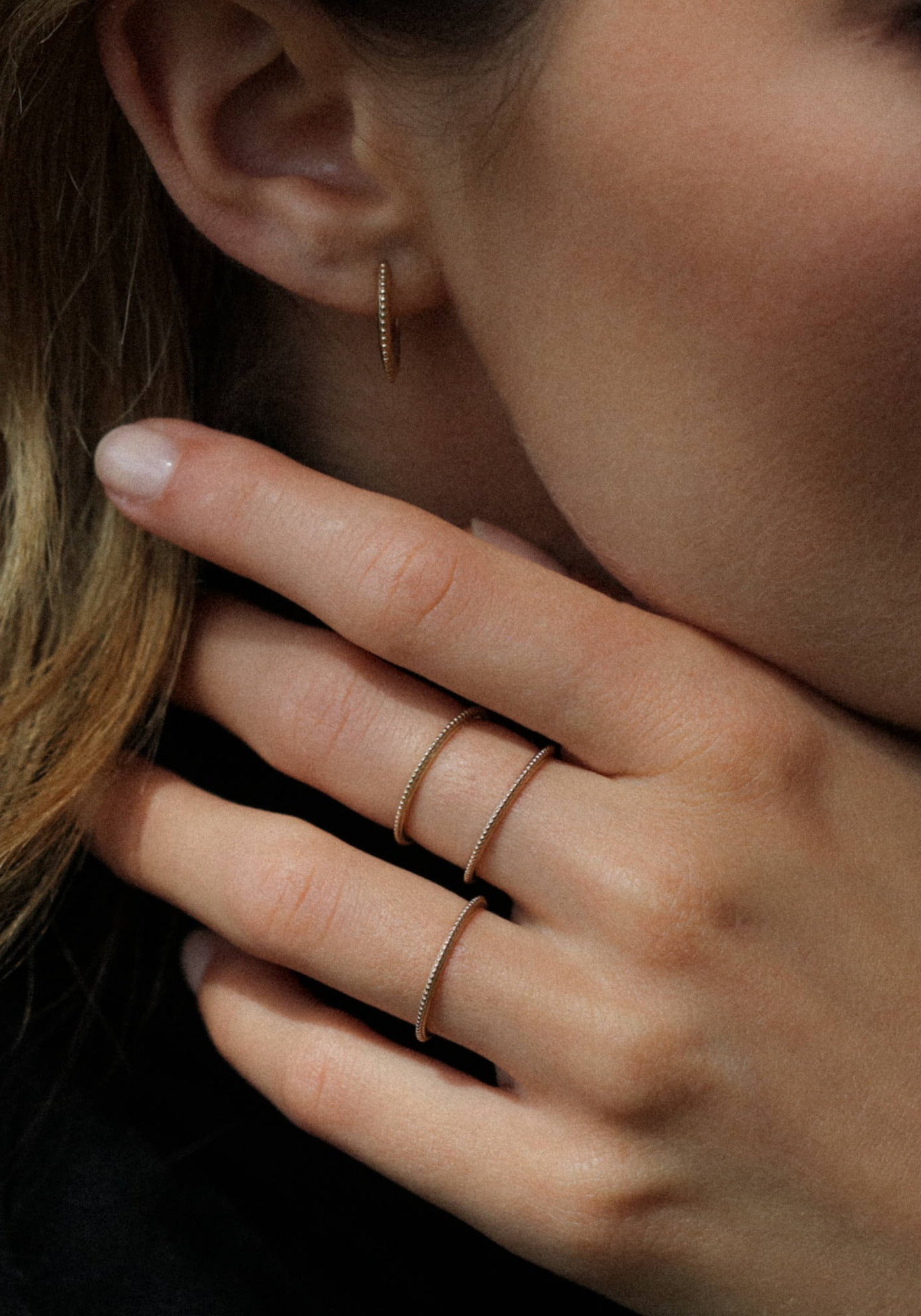 La femme porte la bague Georgia en or jaune de chez Angèle Brousse en ayant la main sur son cou.