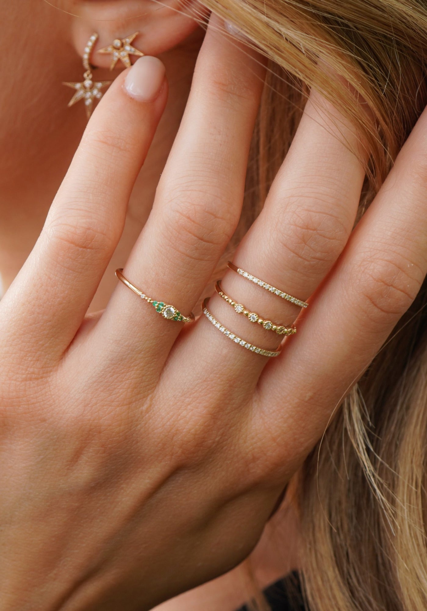 La femme porte la bague Nina Small en or jaune de chez Angèle Brousse en ayant la main dans les cheveux.