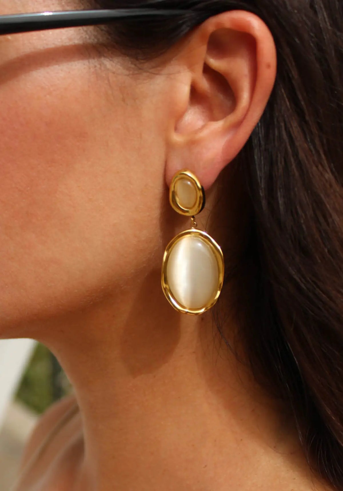 La femme porte les boucles d'oreilles Allegra de chez Caprice Paris