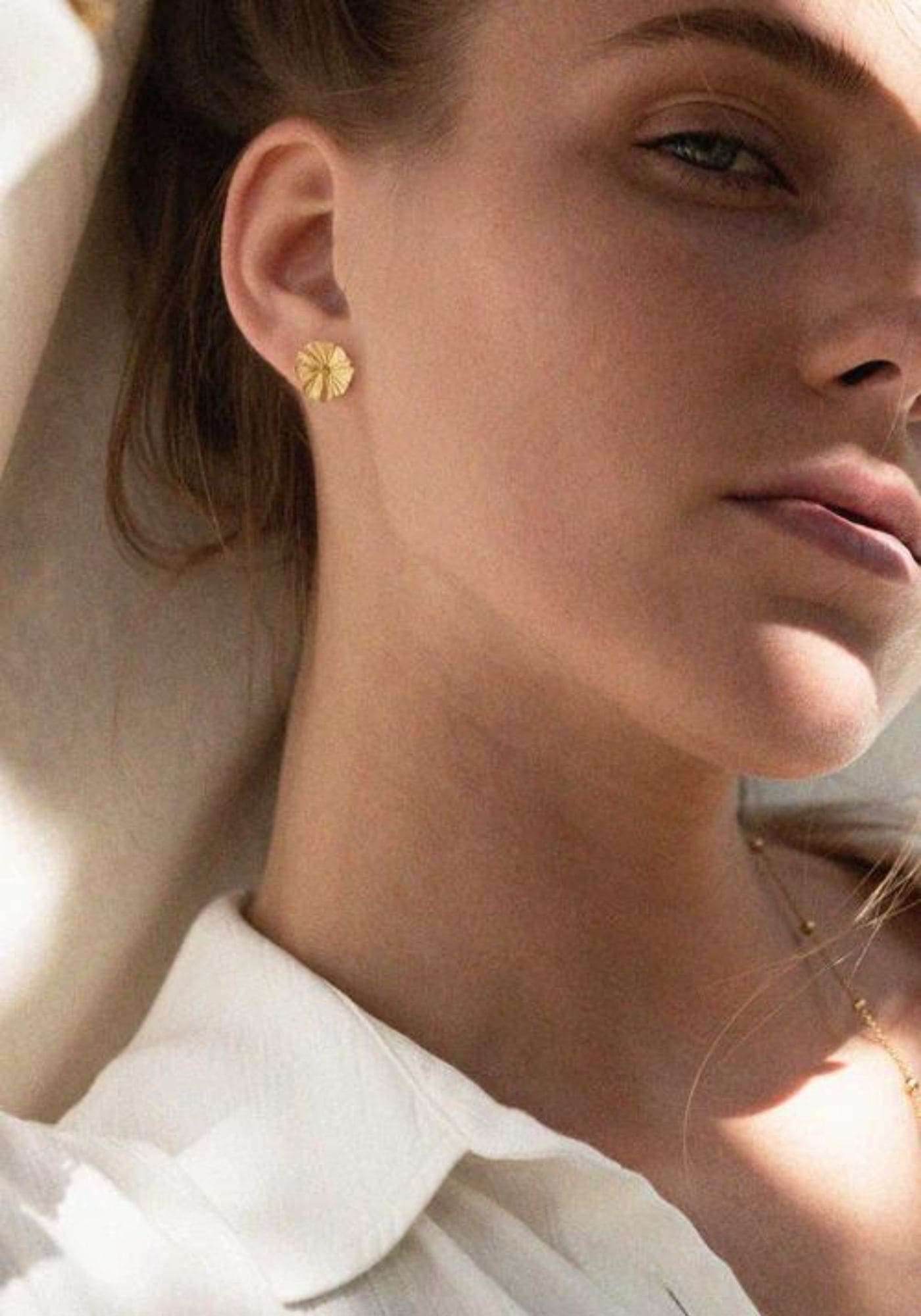 La femme porte les boucles d'oreilles Giulia de chez Bacci Paris