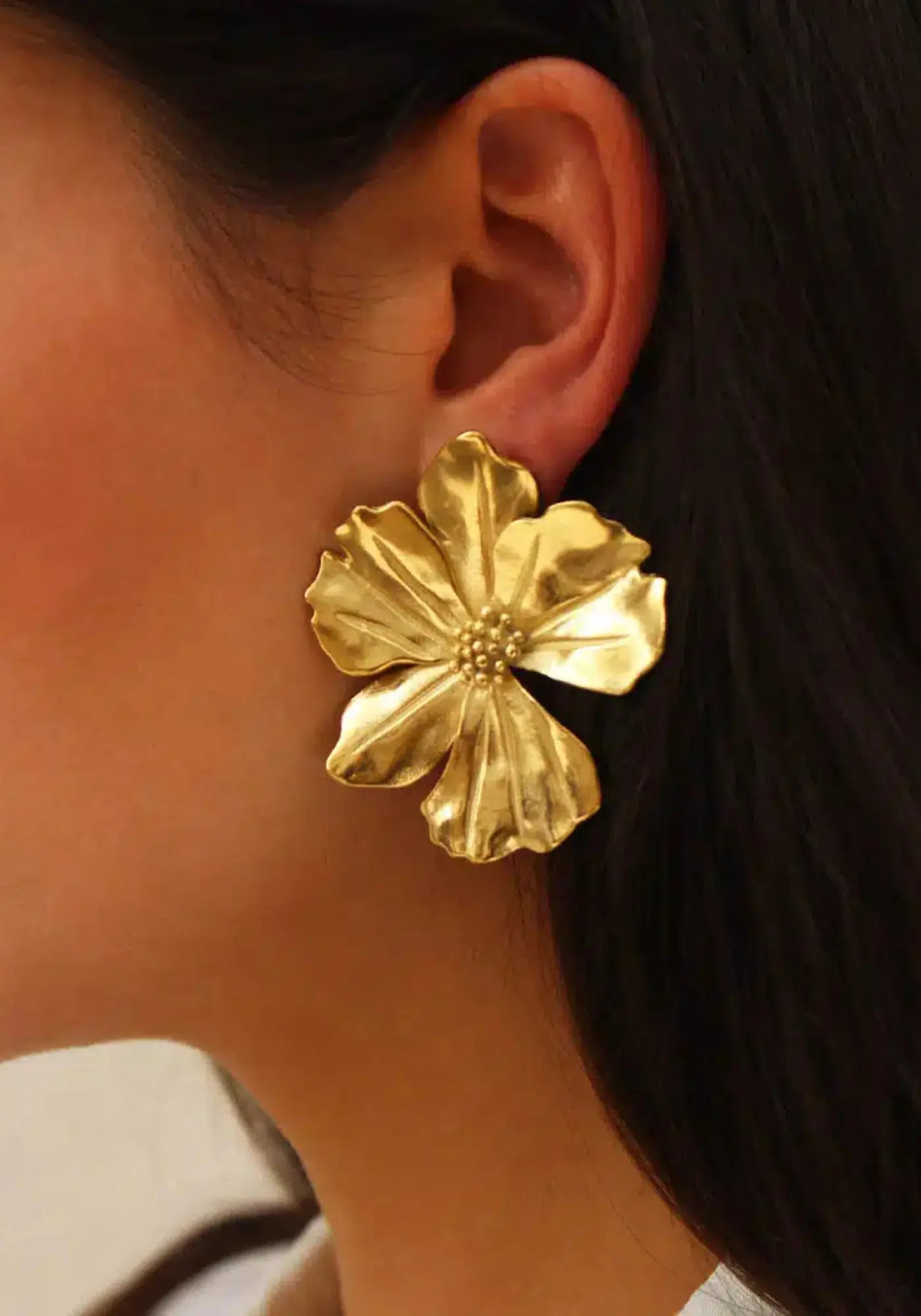 La femme porte les boucles d'oreilles Vicky Or de chez Caprice Paris