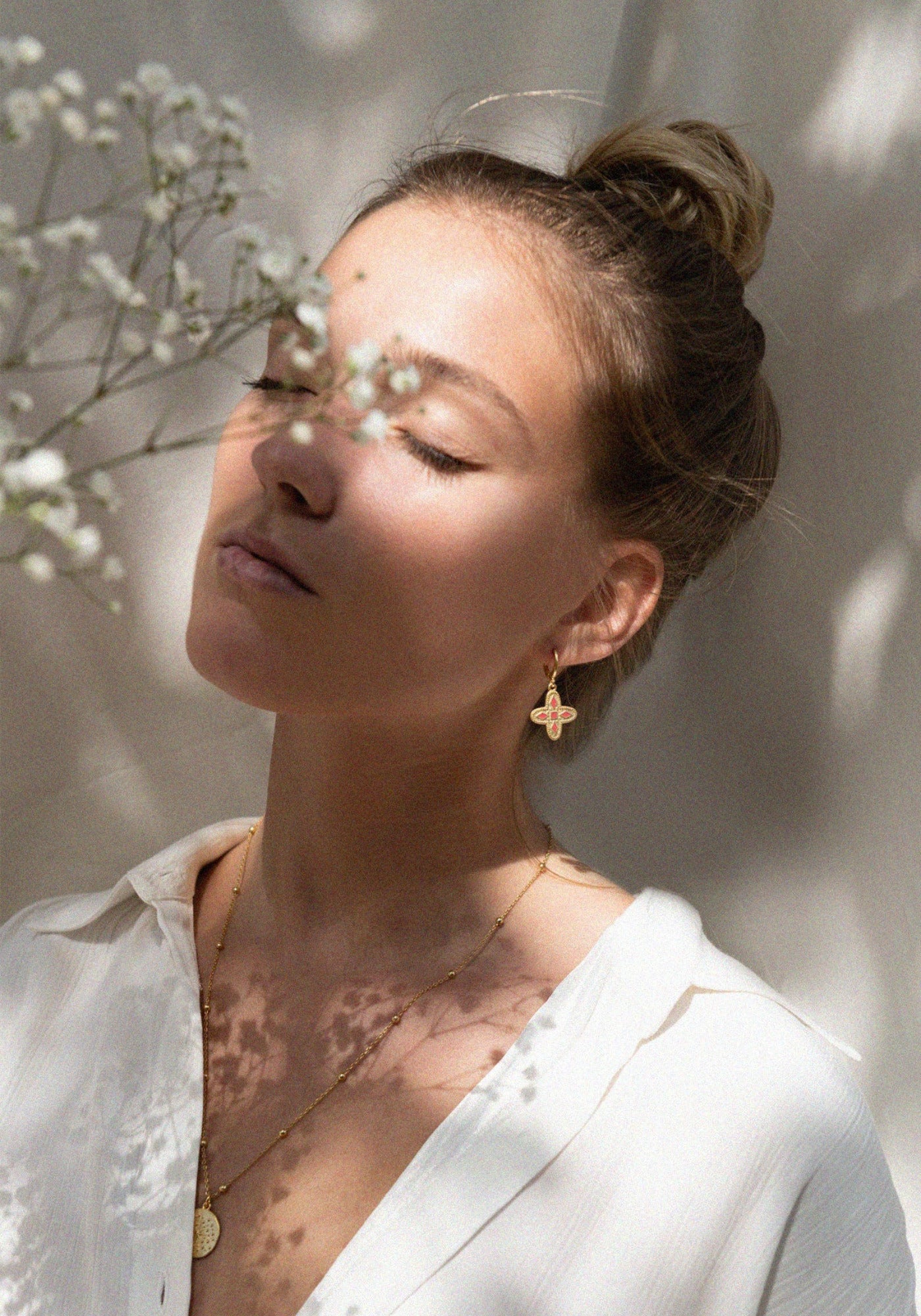 La femme porte les boucles d'oreilles Adriana rouge tangerine de chez Bacci Paris