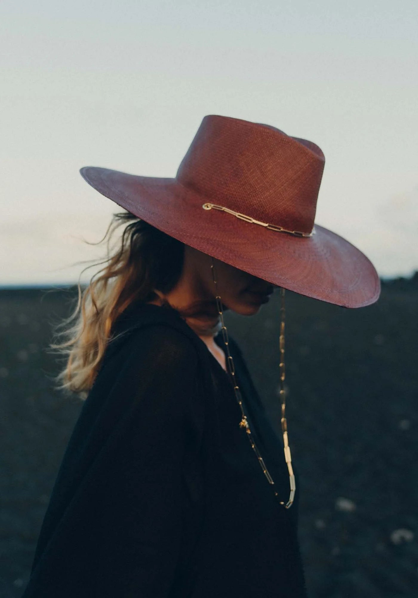 La femme porte le chapeau de paille avec chaîne Livy Junior auburn de chez Van Palma