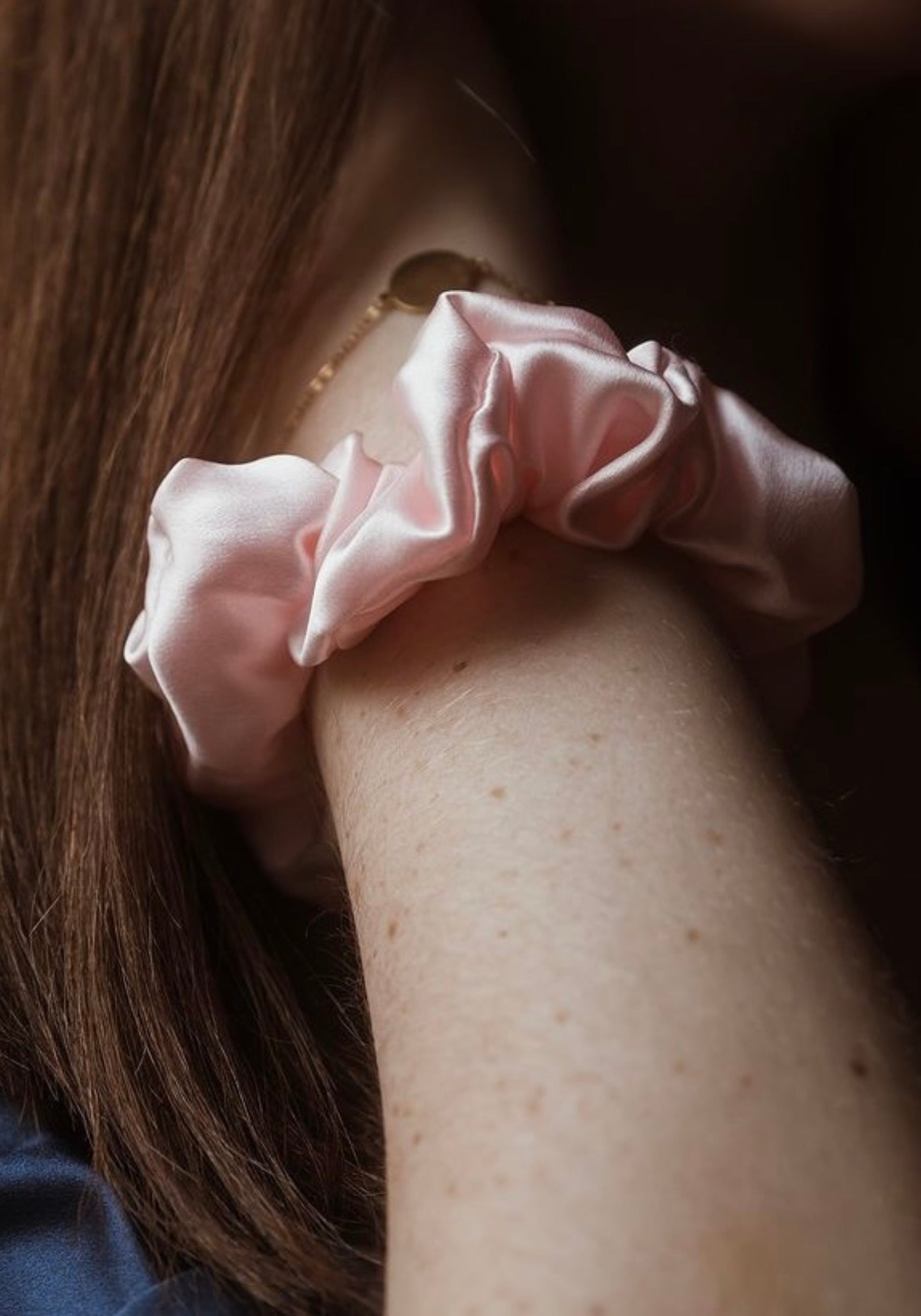 La femme porte à son poignet le chouchou en soie rose de chez Emily's Pillow