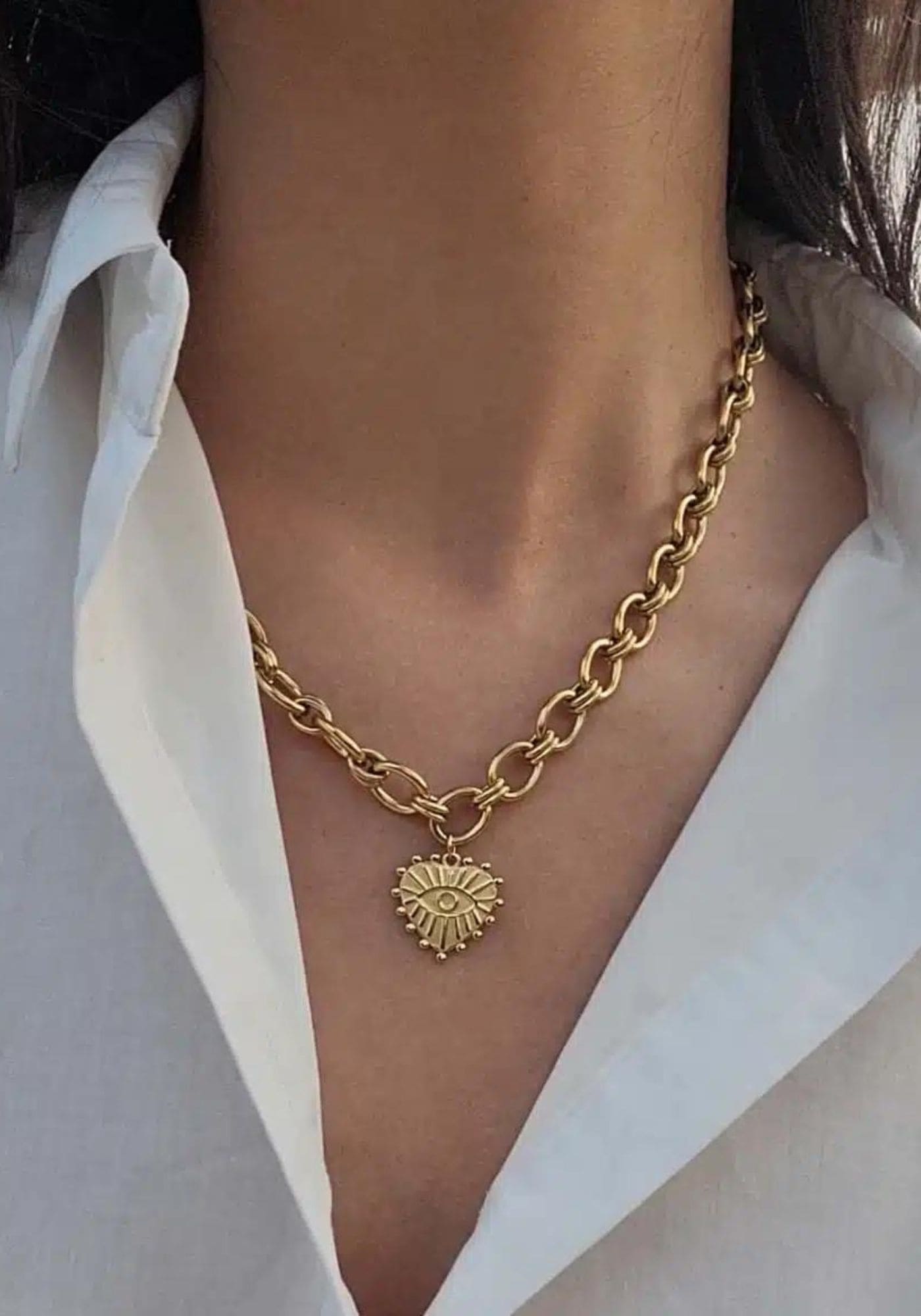 La femme porte le collier Judith de chez Caprice Paris sur une chemise blanche au col ouvert. 