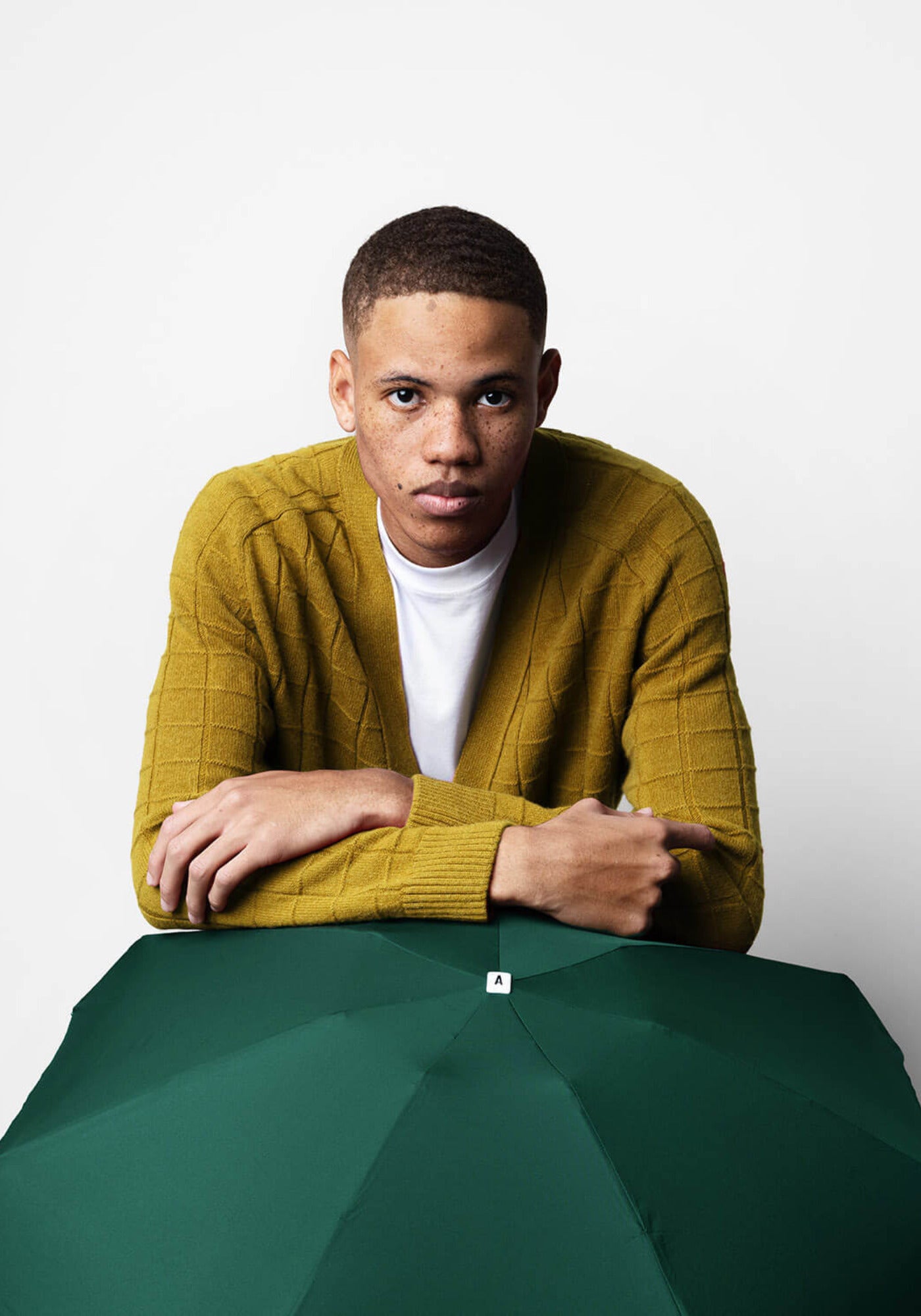 L'homme est appuyé sur le parapluie Gustave vert de chez Anatole