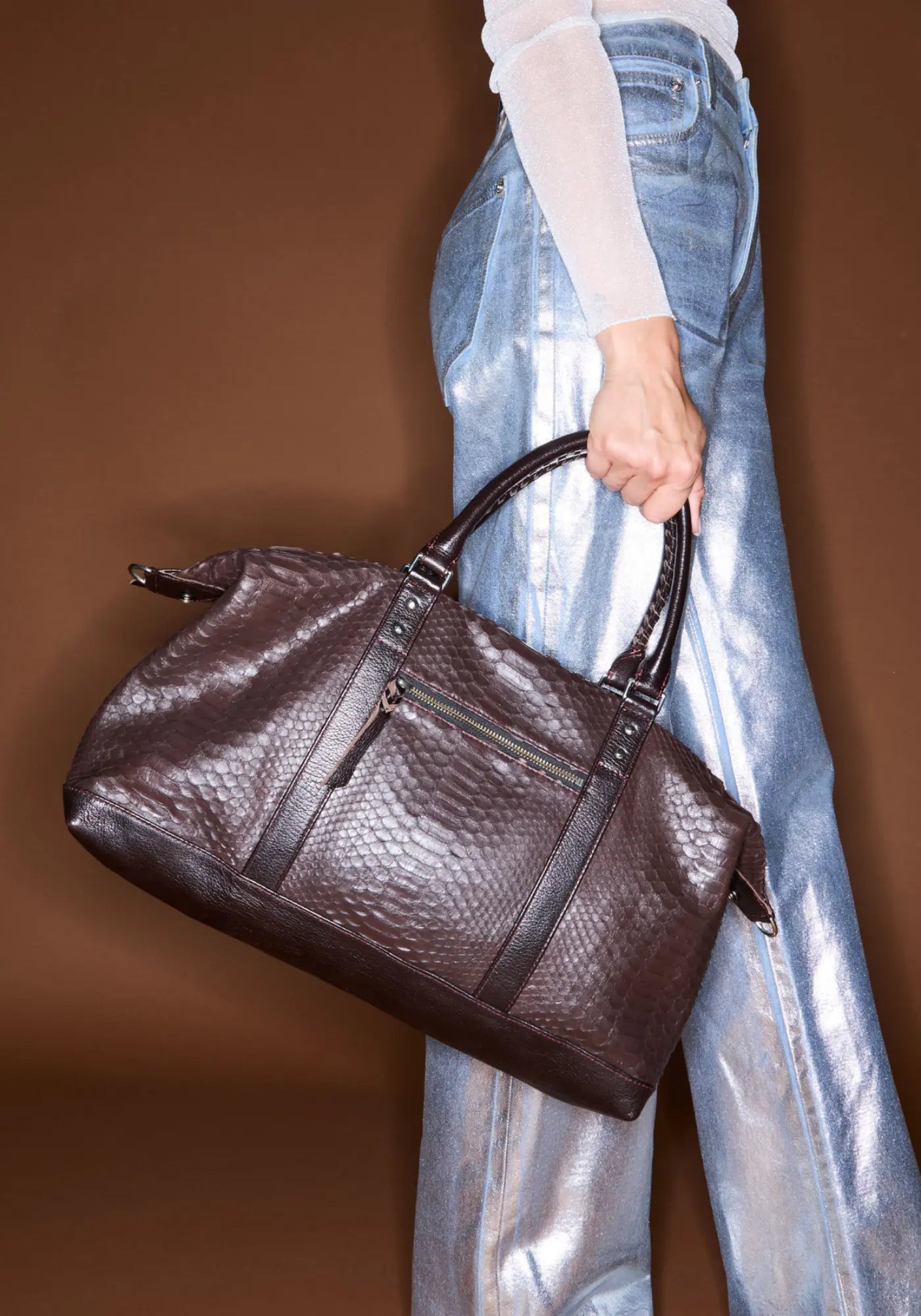 La femme porte le sac week-end Roger brun fumé de chez Claris Virot