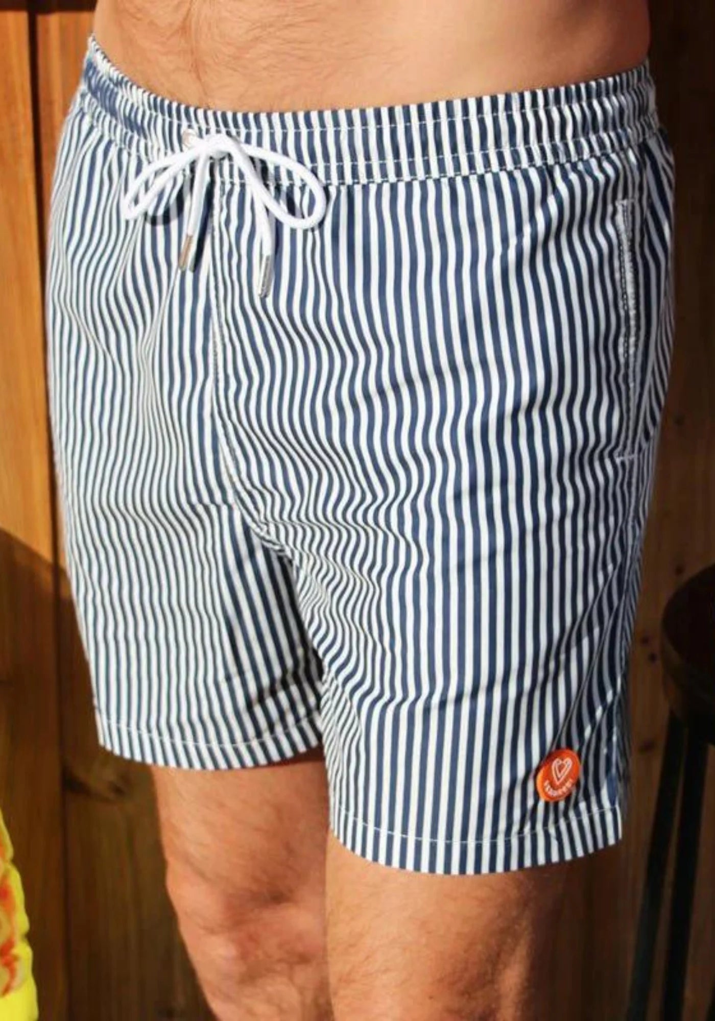 L'homme porte le short de bain L'immergé rayé de chez Vendredi Swimwear