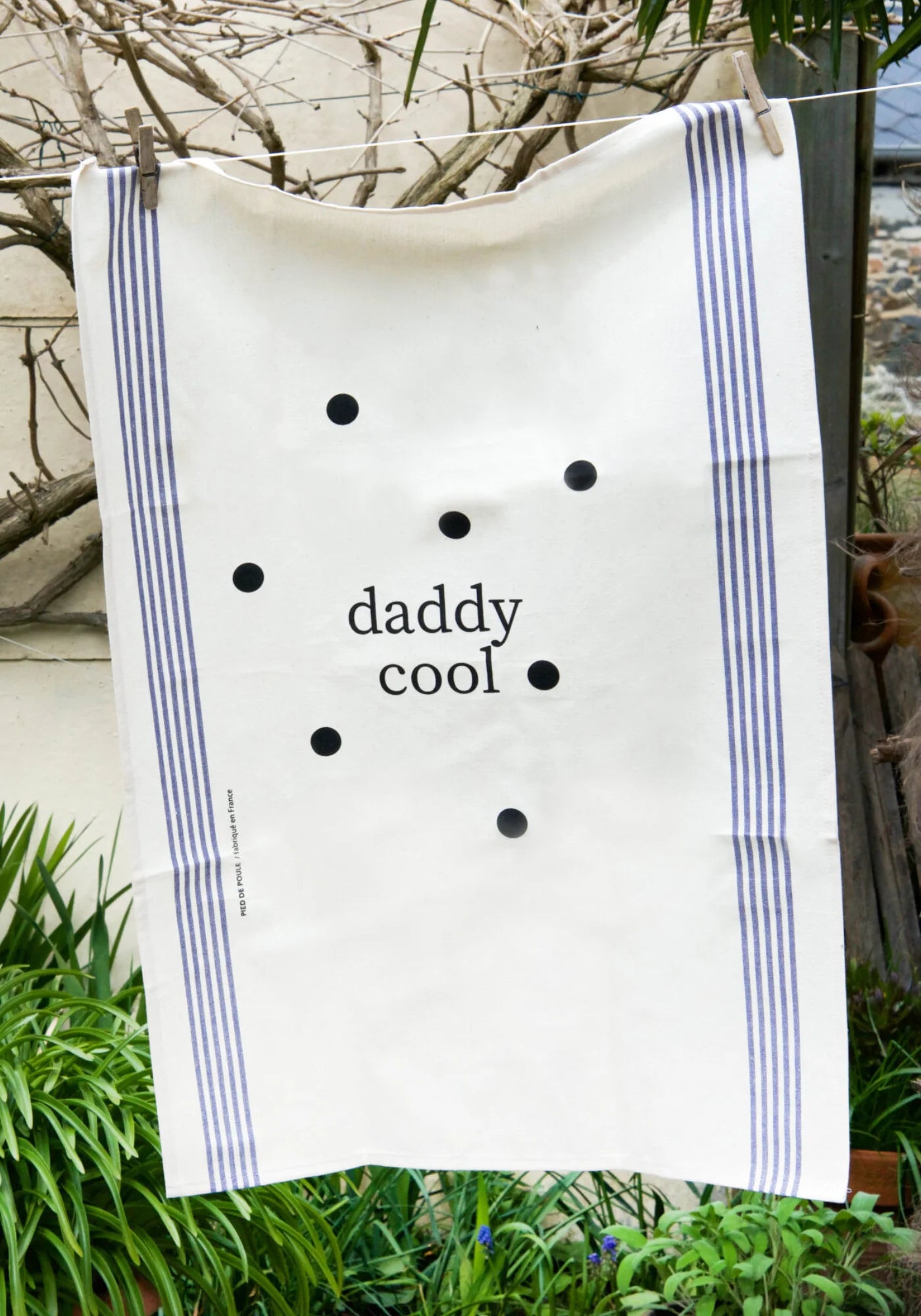 Le torchon en coton naturel Famille Daddy Cool de chez Pied de Poule suspendu à un fil dehors