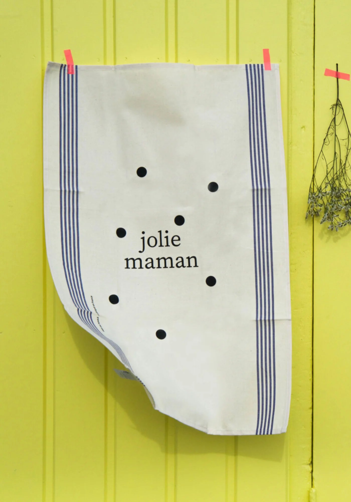 Le torchon en coton naturel Famille Jolie Maman de chez Pied de Poule scotché sur une porte de garage jaune fluo
