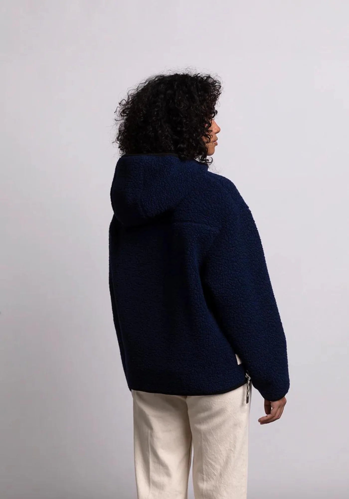 la femme est de dos et porte la veste sherpa unisexe hood bleu marine de chez mout mout 