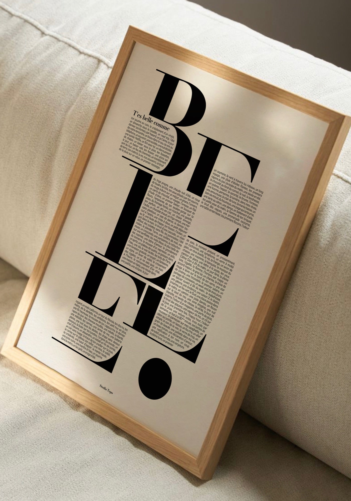 L'affiche typographique "T'es belle comme" en 30x40 cm de chez Studio Topo posée sur un canapé