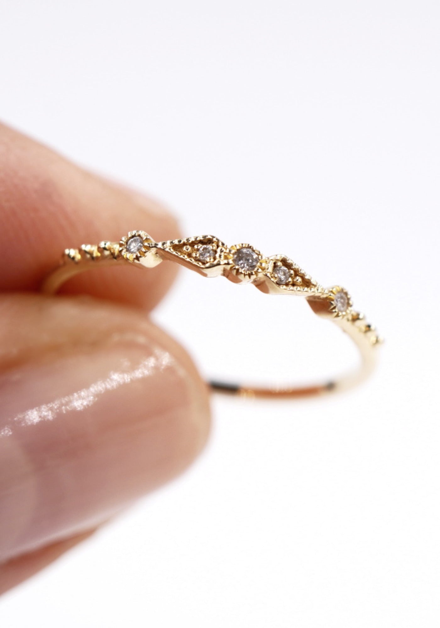 La femme porte entre ses doigts la bague Stella 5 Diamants en or jaune de chez Angèle Brousse.