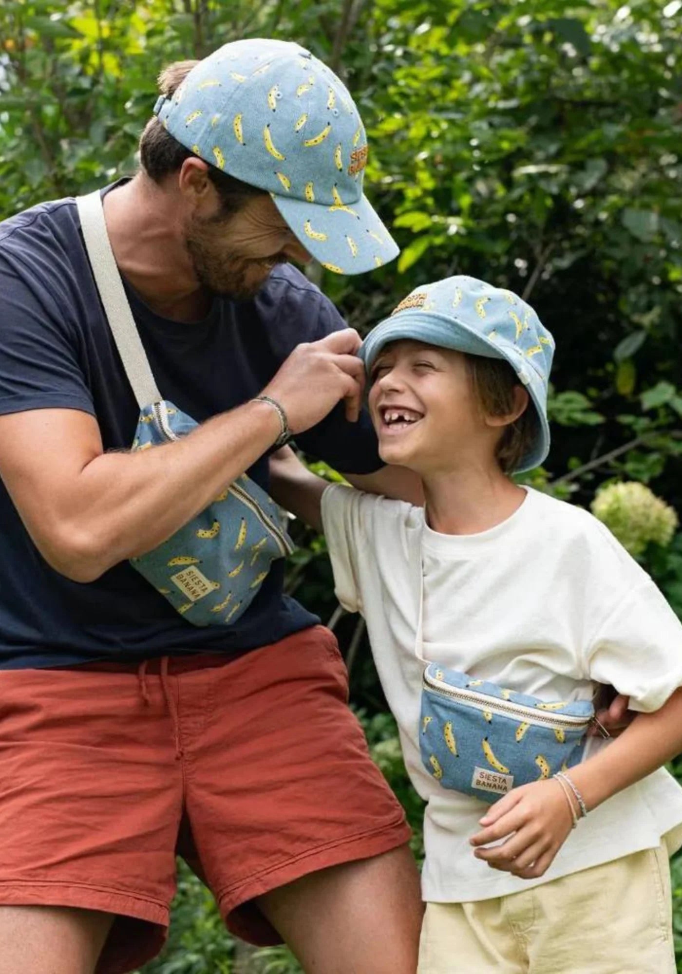 Le petit garçon rigole avec son père et porte le sac banane Siesta Banana de chez Chamaye