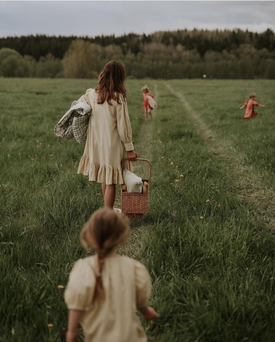 Image de petites filles qui courent dans la prairie avec un panier à la main