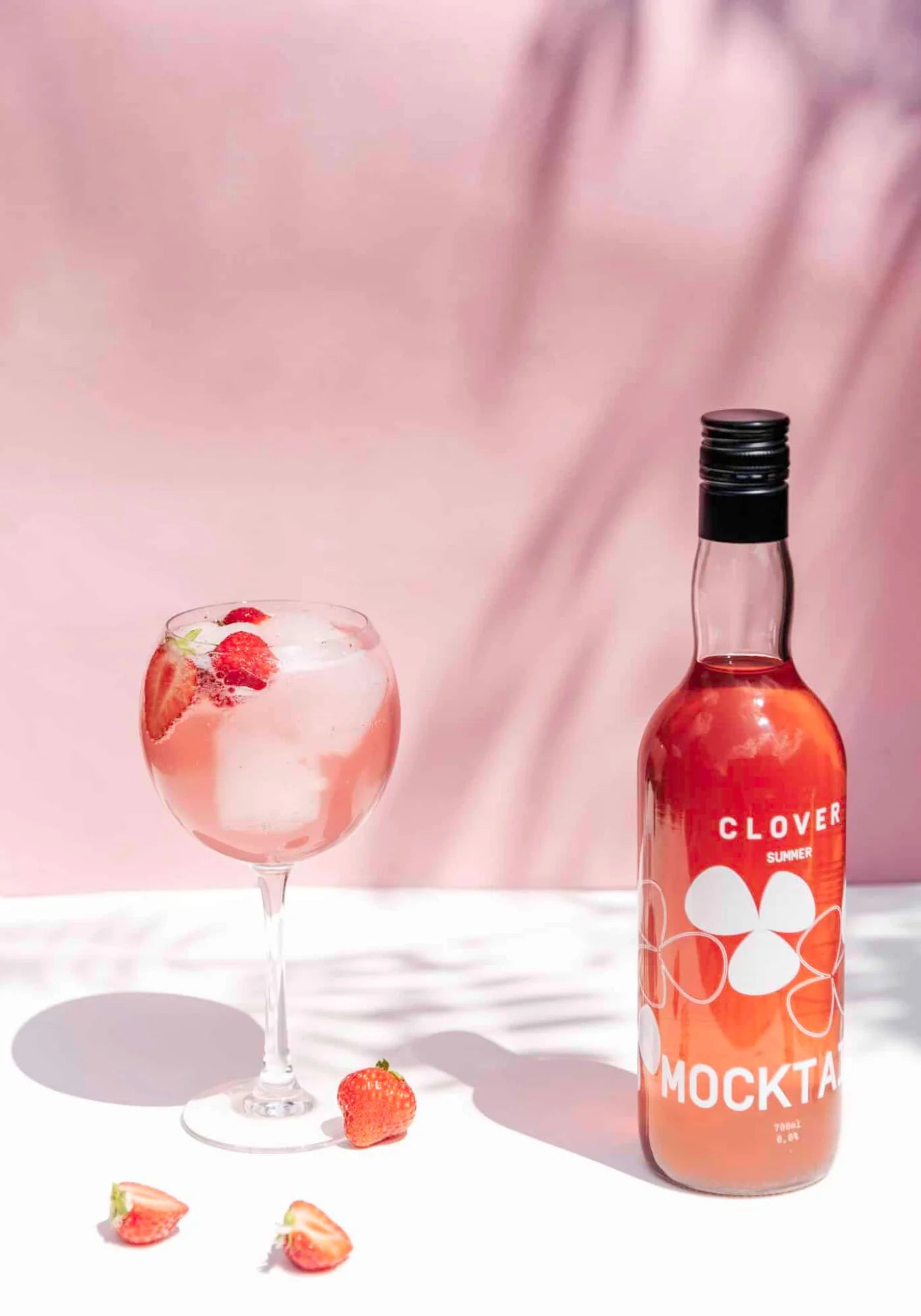 La boisson sans alcool Mocktail de chez Clover Gin accompagnée d'un verre rempli et de fraises