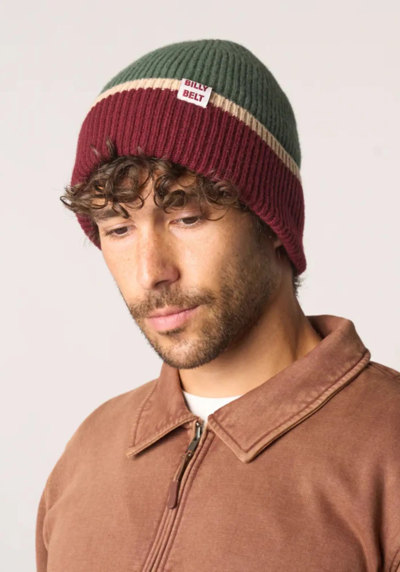 L'homme porte le bonnet en laine kaki bordeaux beige de chez Billybelt