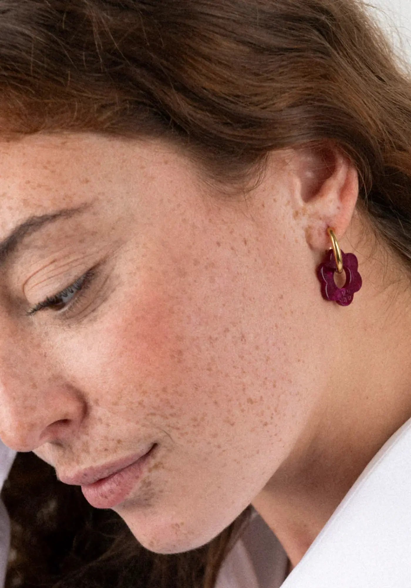 La femme porte les boucles d'oreilles fleurette cerise baby de chez Kurage Ginza