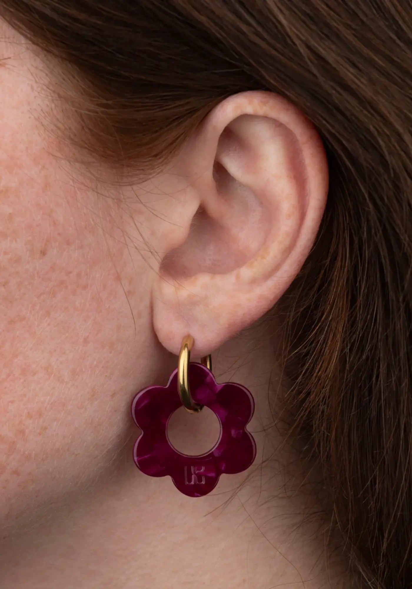 La femme porte les boucles d'oreilles fleurette cerise maxi de chez Kurage Ginza