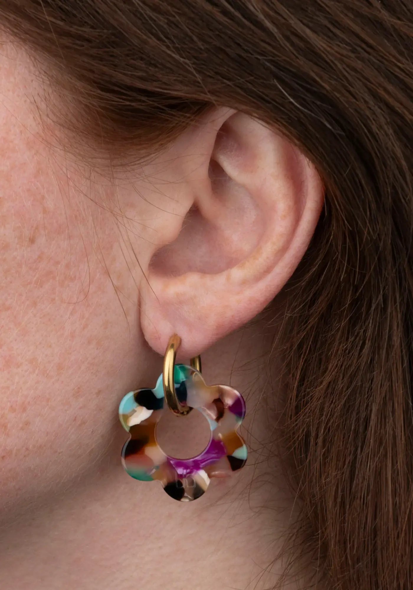 La femme porte les boucles d'oreilles fleurette confettis maxi de chez Kurage Ginza