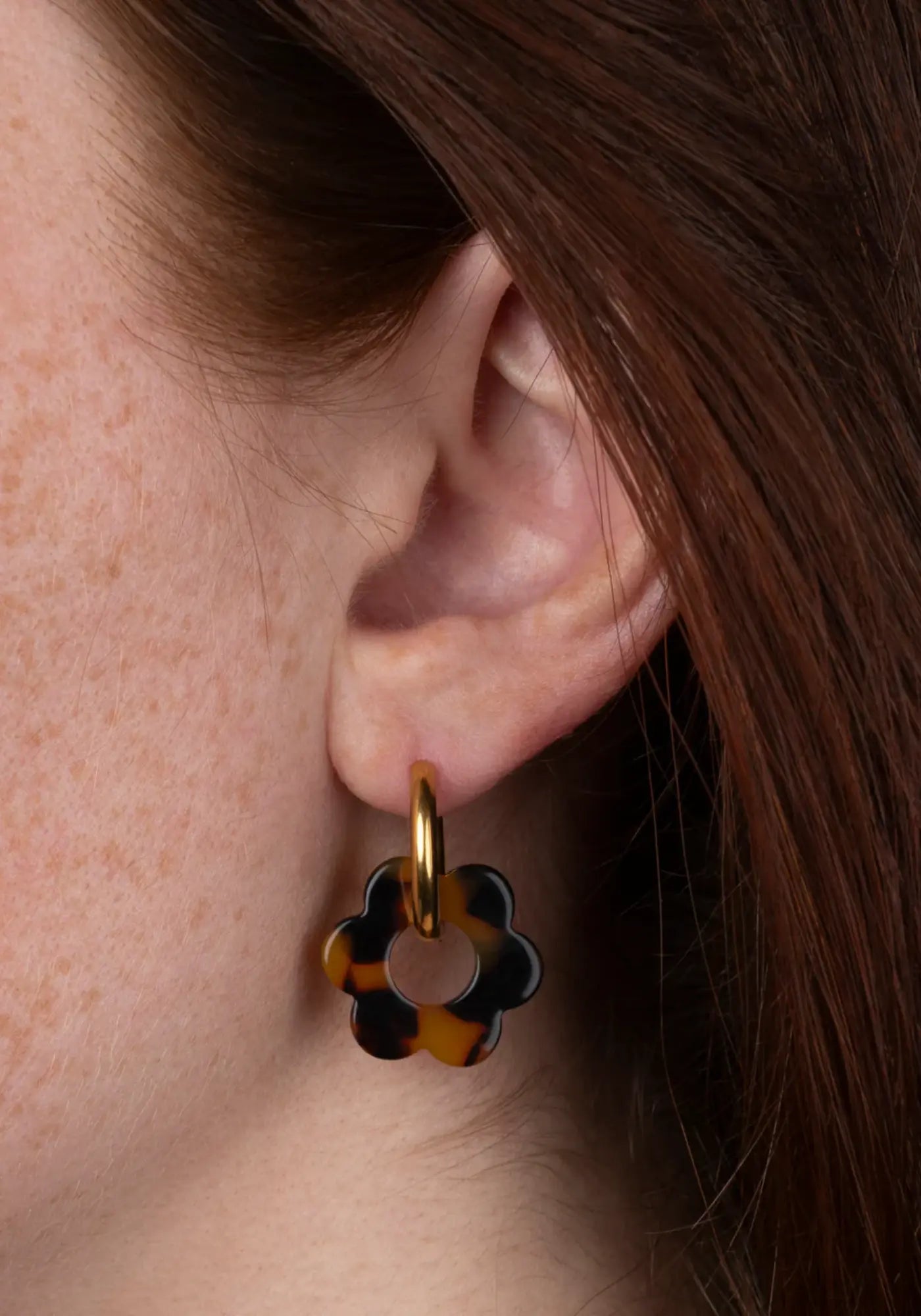 La femme porte les boucles d'oreilles fleurette écaille baby de chez Kurage Ginza