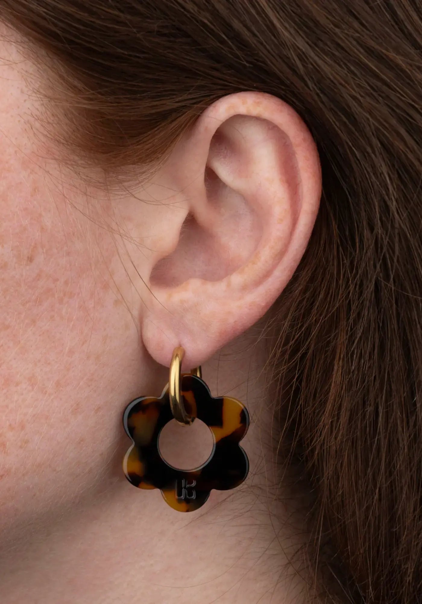 La femme porte les boucles d'oreilles fleurette écaille maxi de chez Kurage Ginza