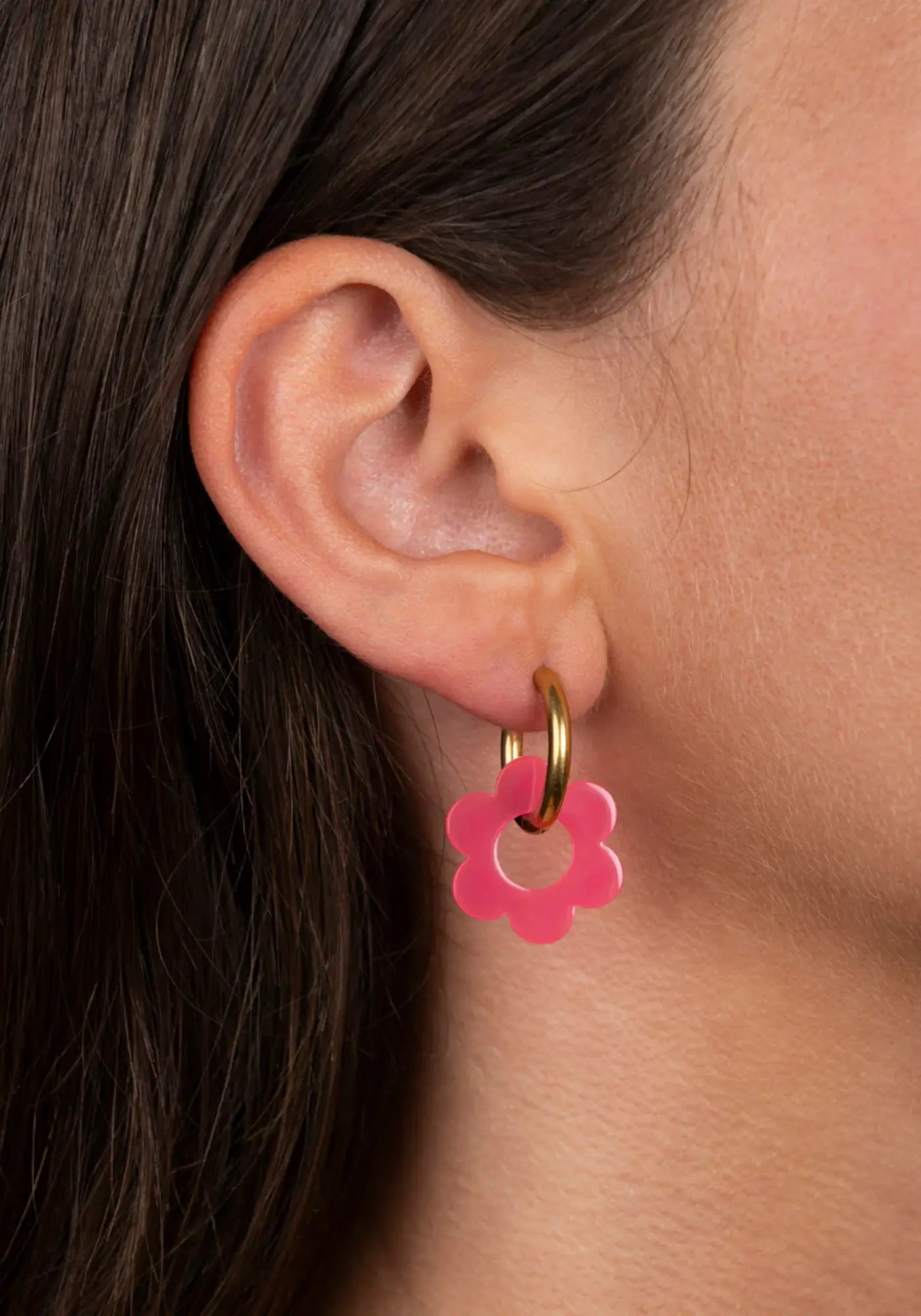 La femme porte les boucles d'oreilles fleurette fuchsia baby de chez Kurage Ginza