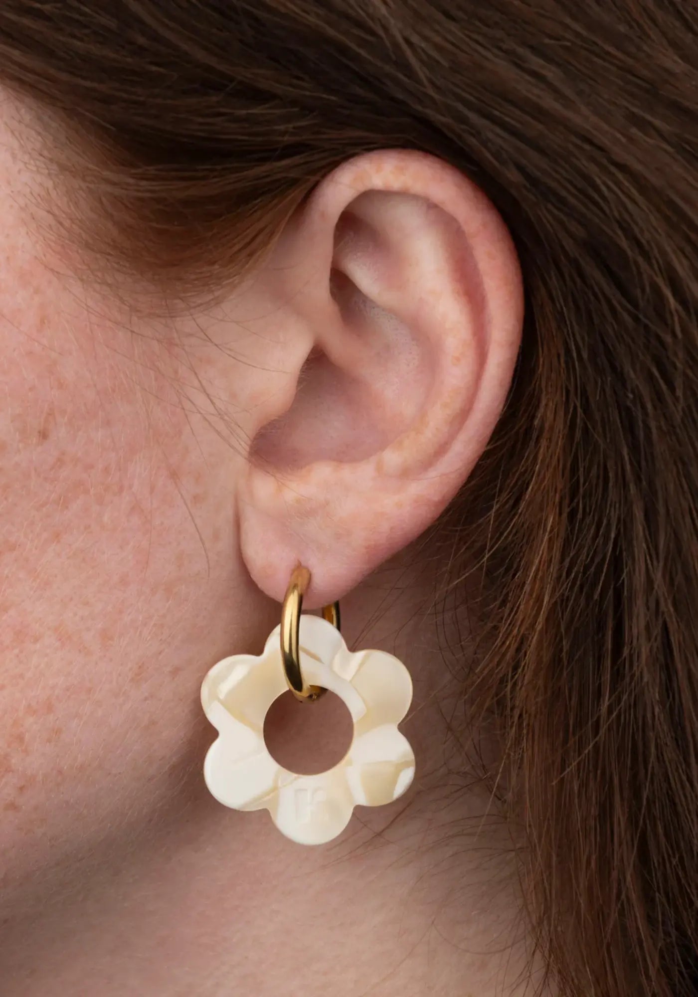 La femme porte les boucles d'oreilles fleurette nude maxi de chez Kurage Ginza