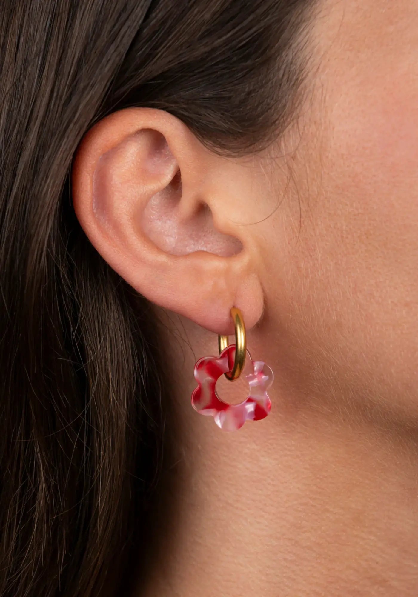 La femme porte les boucles d'oreilles fleurette rouge baby de chez Kurage Ginza