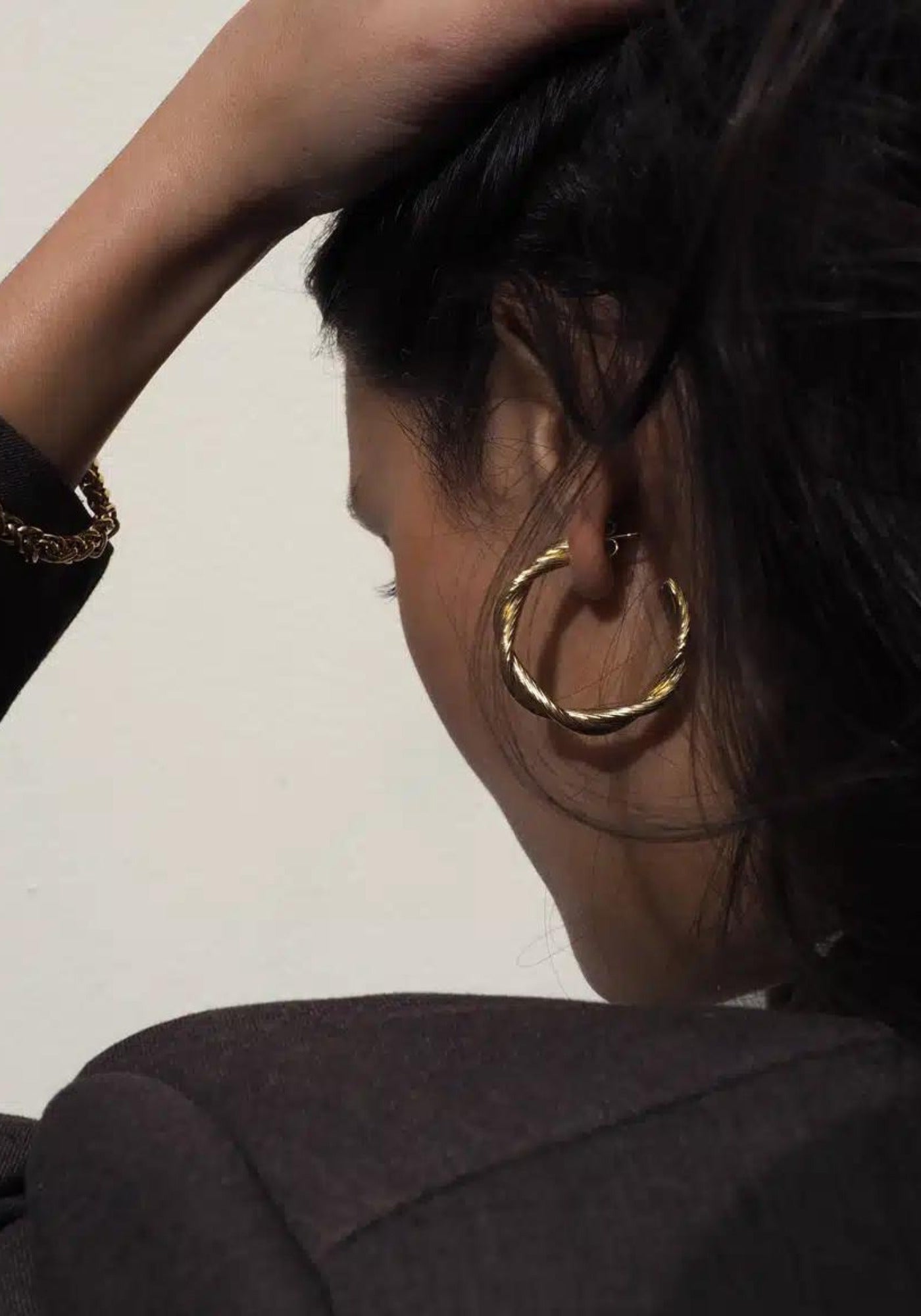 La femme porte les boucles d'oreilles Déméter en or de chez Caprice Paris