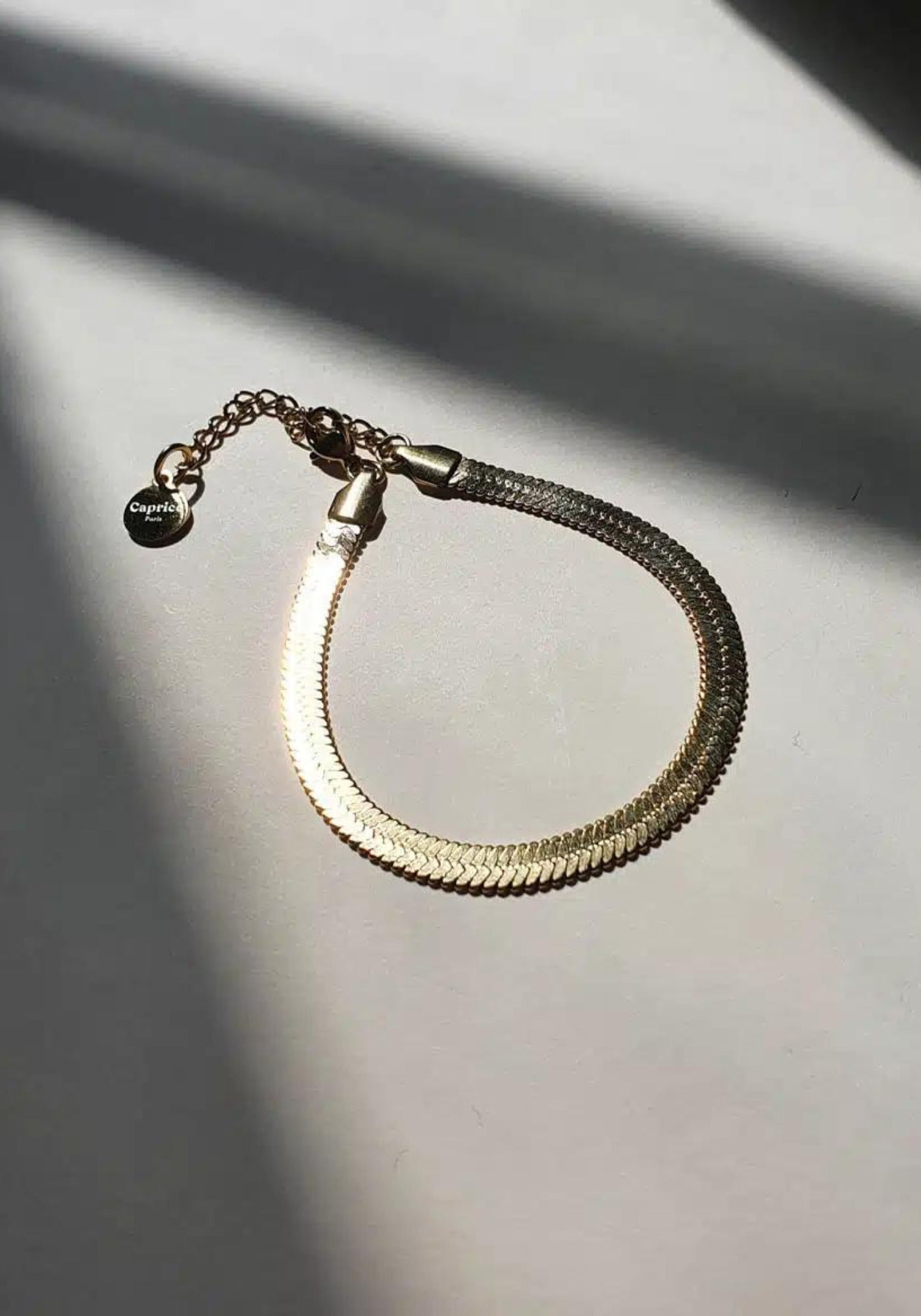 Le bracelet Leto en or pour femme posé sur une table au soleil de chez Caprice Paris 