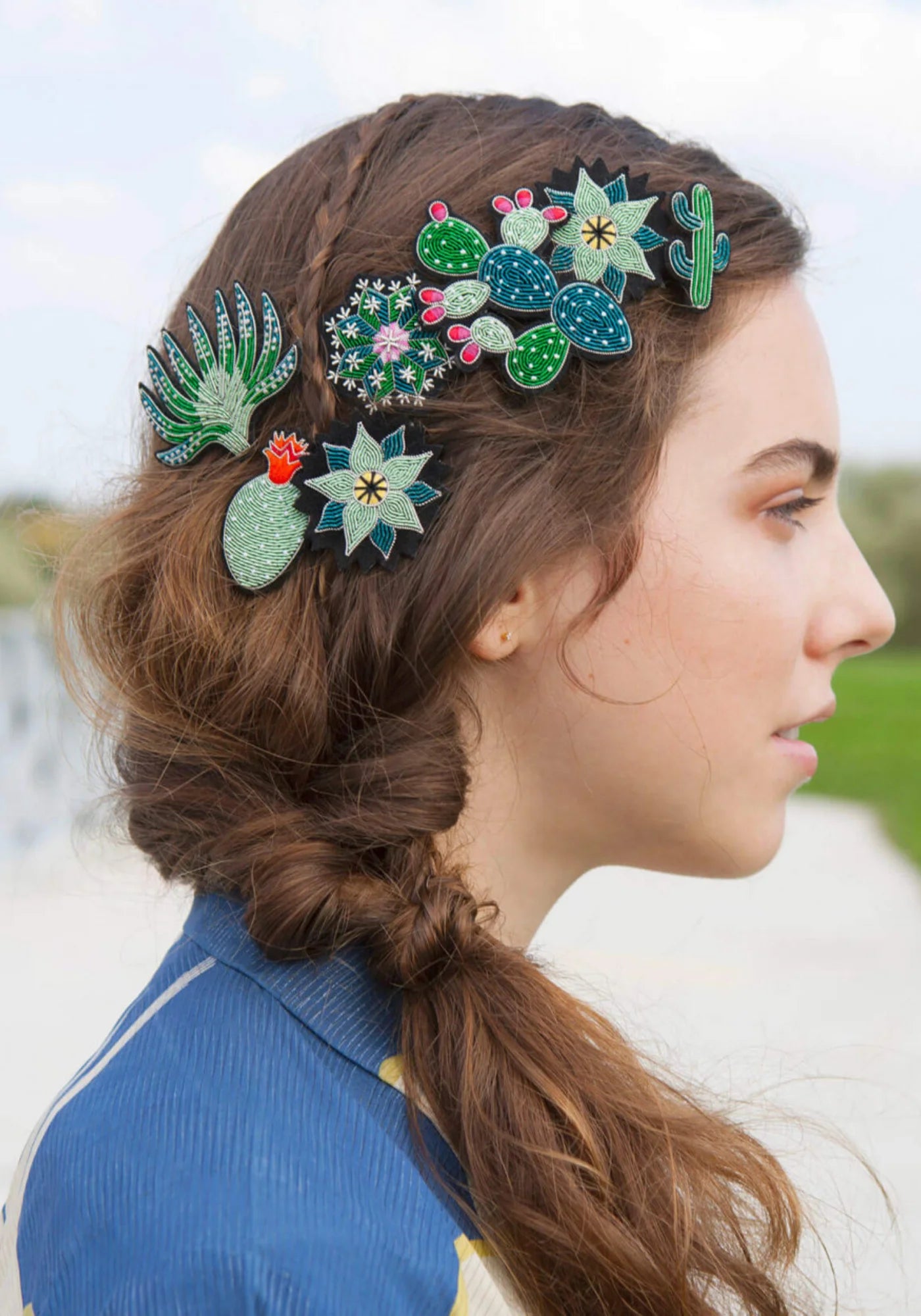 La femme porte dans ses cheveux la broche brodée à la main Mini cactus de chez Macon & Lesquoy