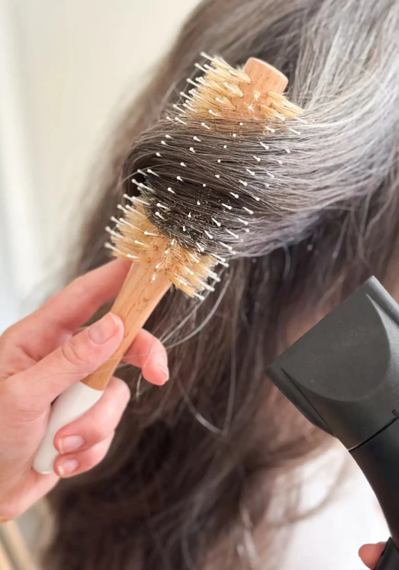 La femme utilise la brosse brushing sanglier/nylon ronde en bois de chez Bachca 