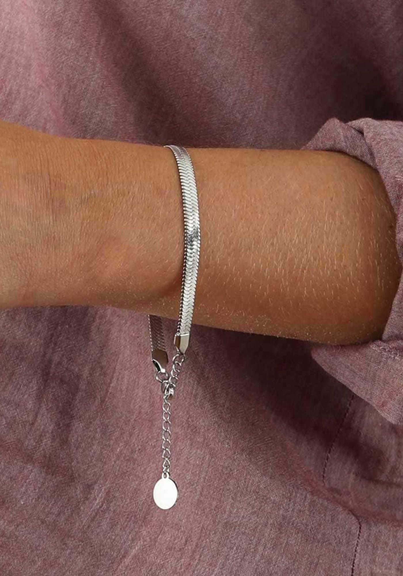 La femme porte le bracelet en argenté de chez Caprice Paris