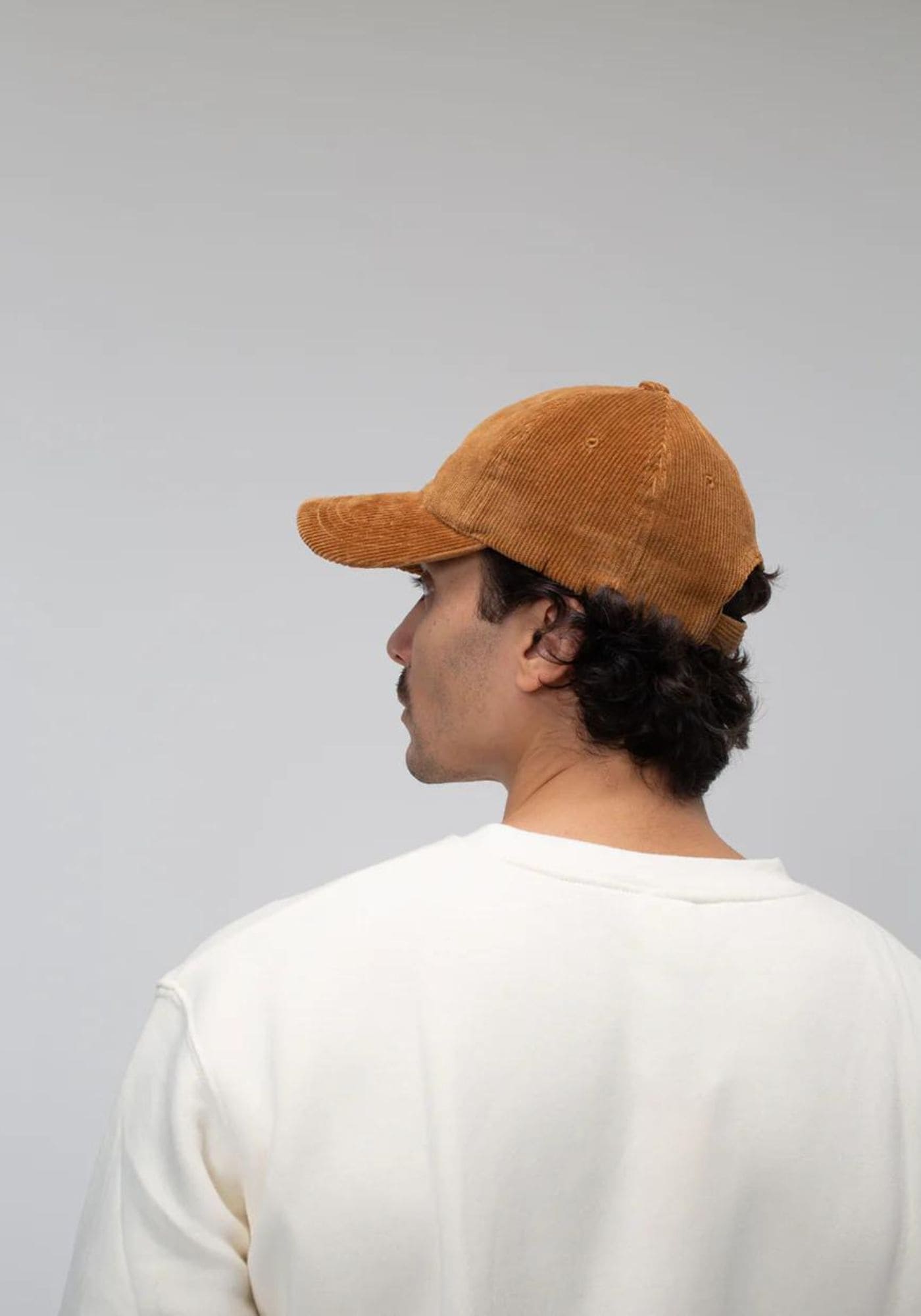 L'homme est de dos et porte la casquette en velours camel de chez Côtelé Paris