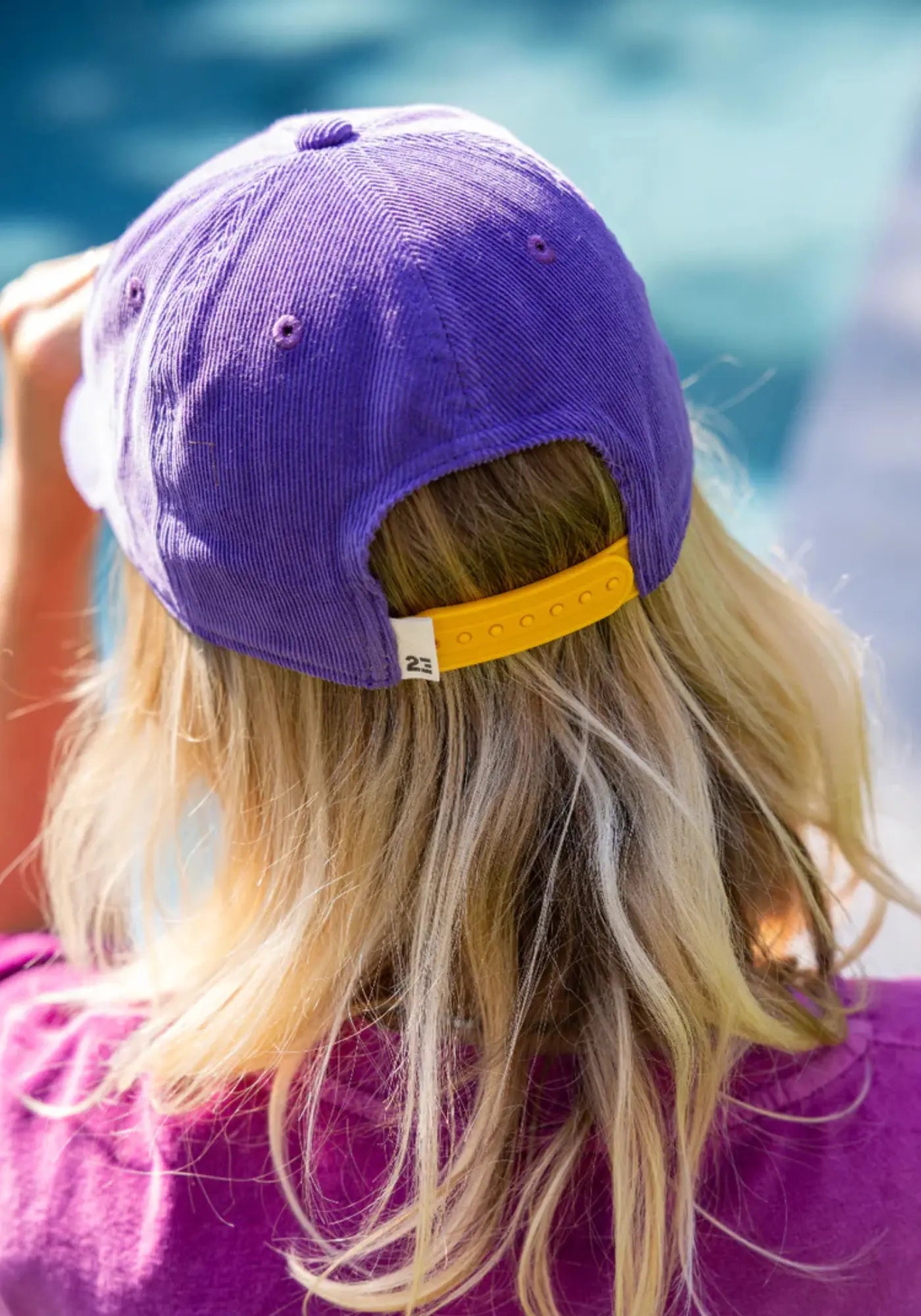 La femme est de dos et porte la casquette violette drop 2 de chez 23 Degres