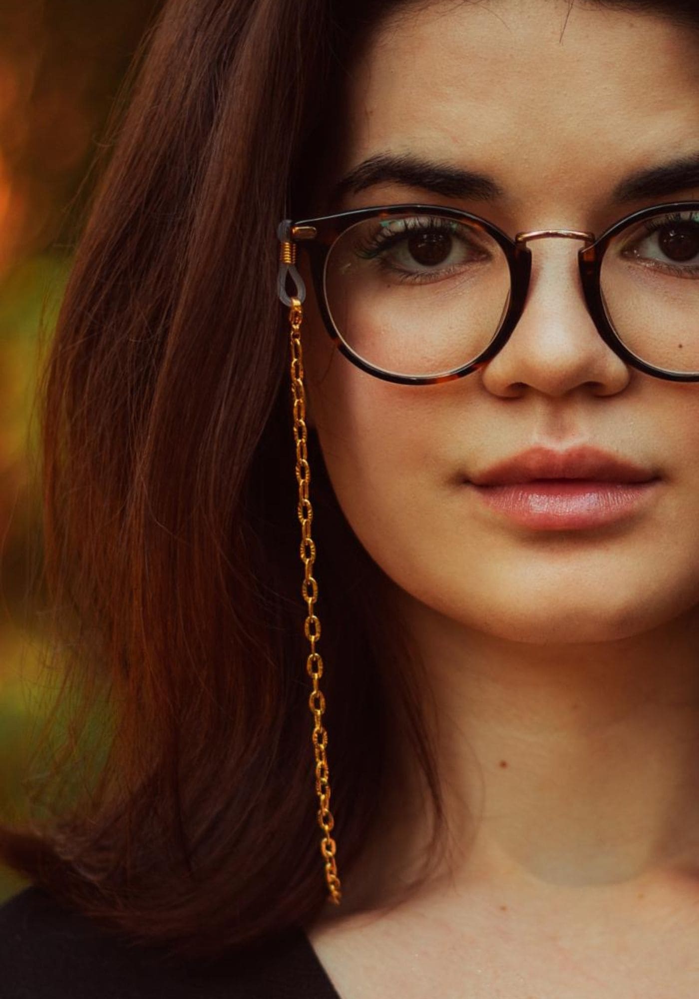 La femme porte des lunettes de vue avec la chaîne de lunettes dorée Phoenix de chez Atelier Kat H
