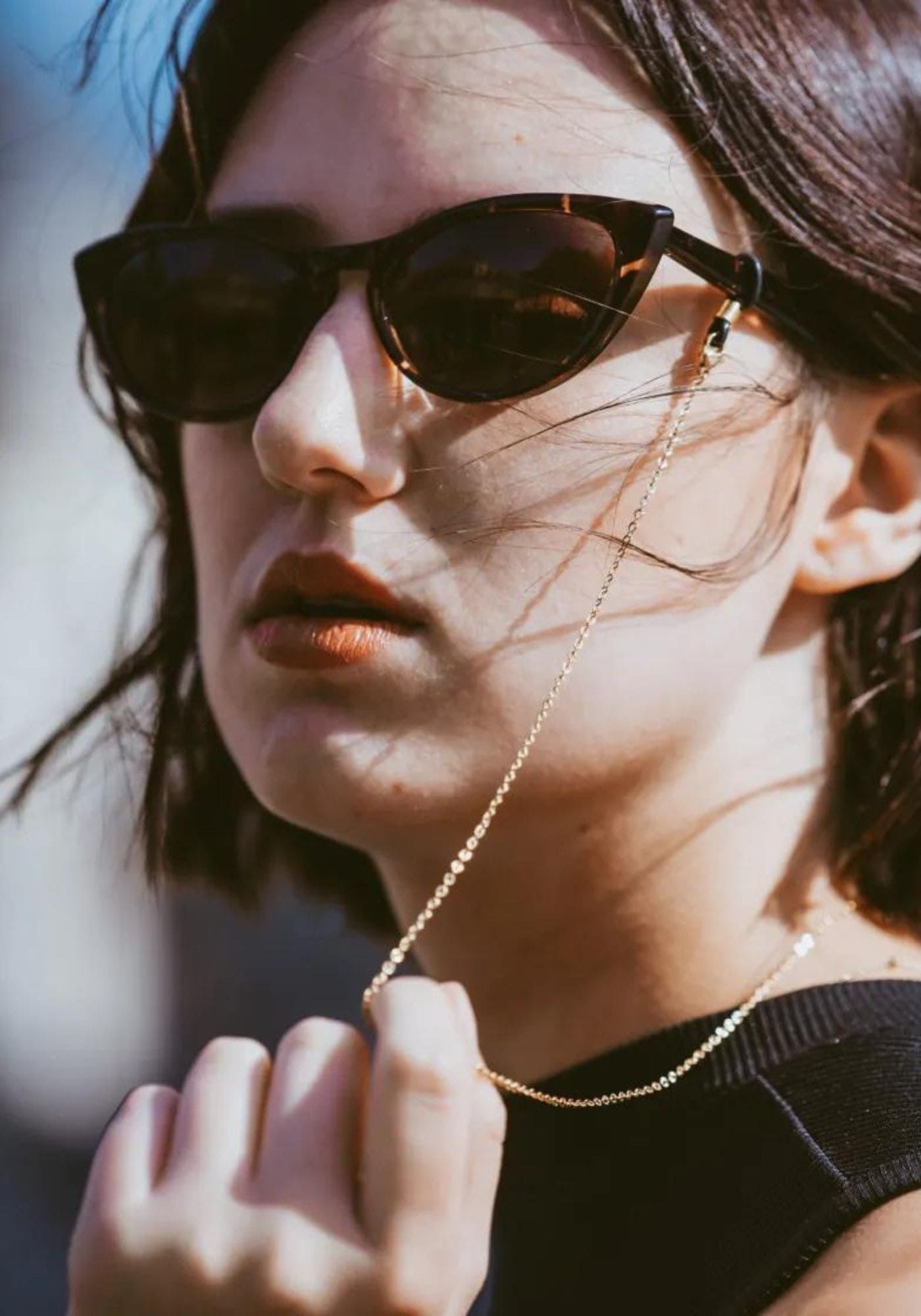 La femme porte des lunettes de soleil avec la chaîne de lunettes Sofia de chez Atelier Kat H