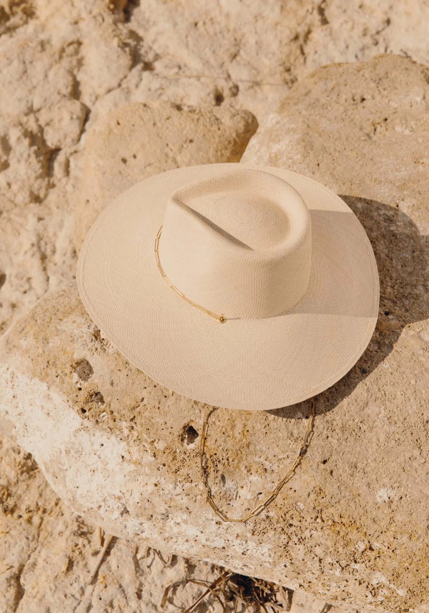 Le chapeau de paille avec chaîne Livy Junior natural pour femme de chez Van Palma posé sur un rocher