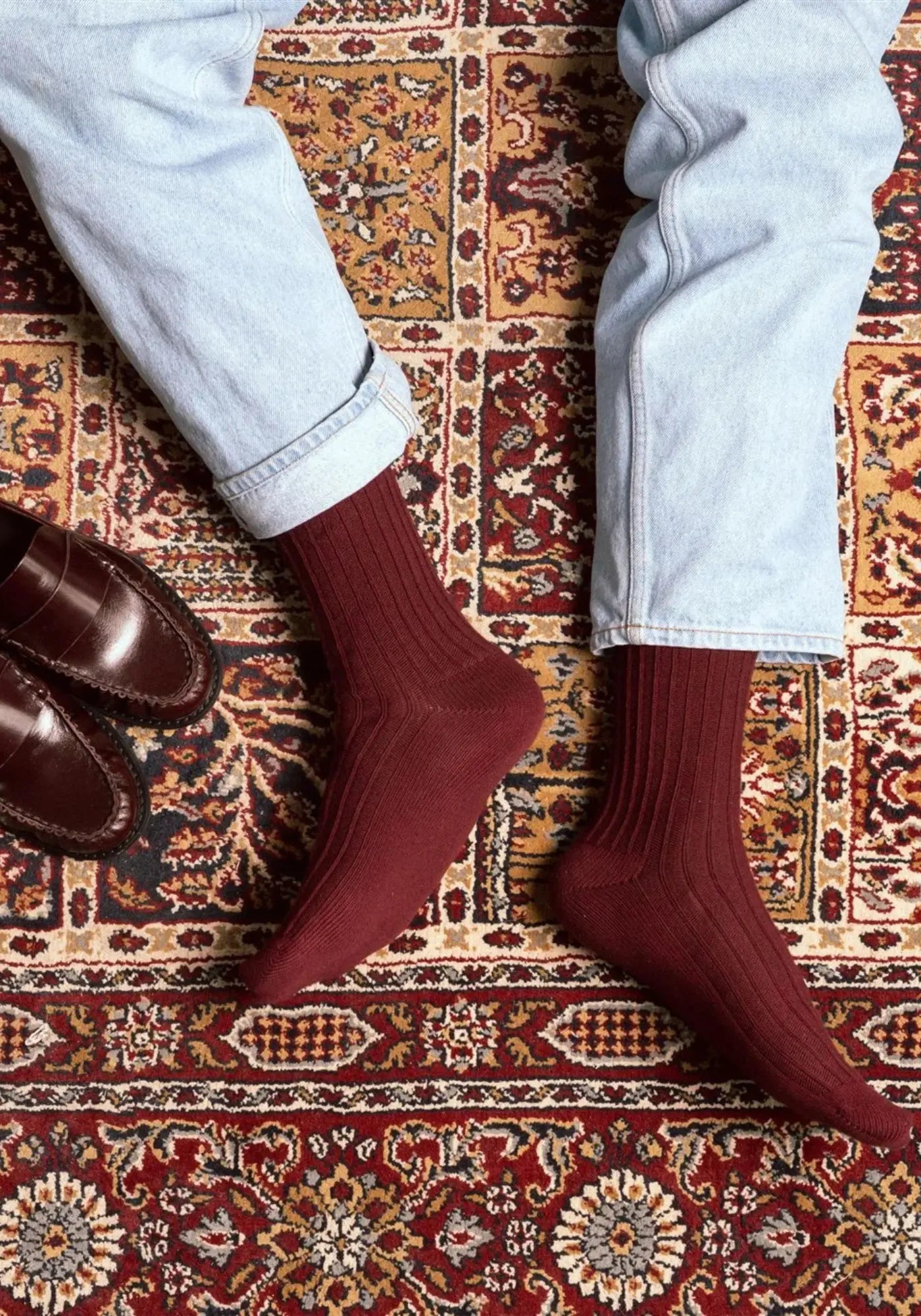 Le mannequin porte les chaussettes en coton biologique burgundy solid knitted de chez Klue