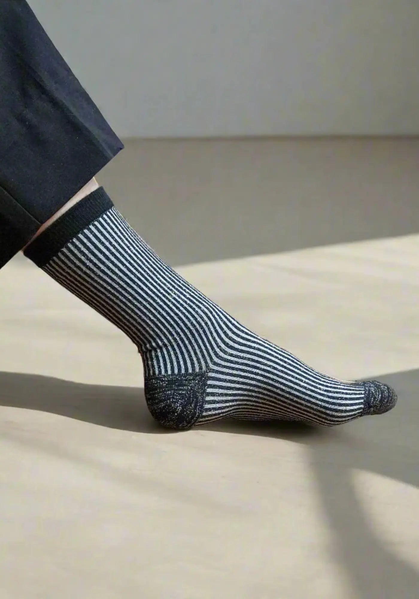 Le mannequin porte les chaussettes lurex à rayures noires de chez Klue