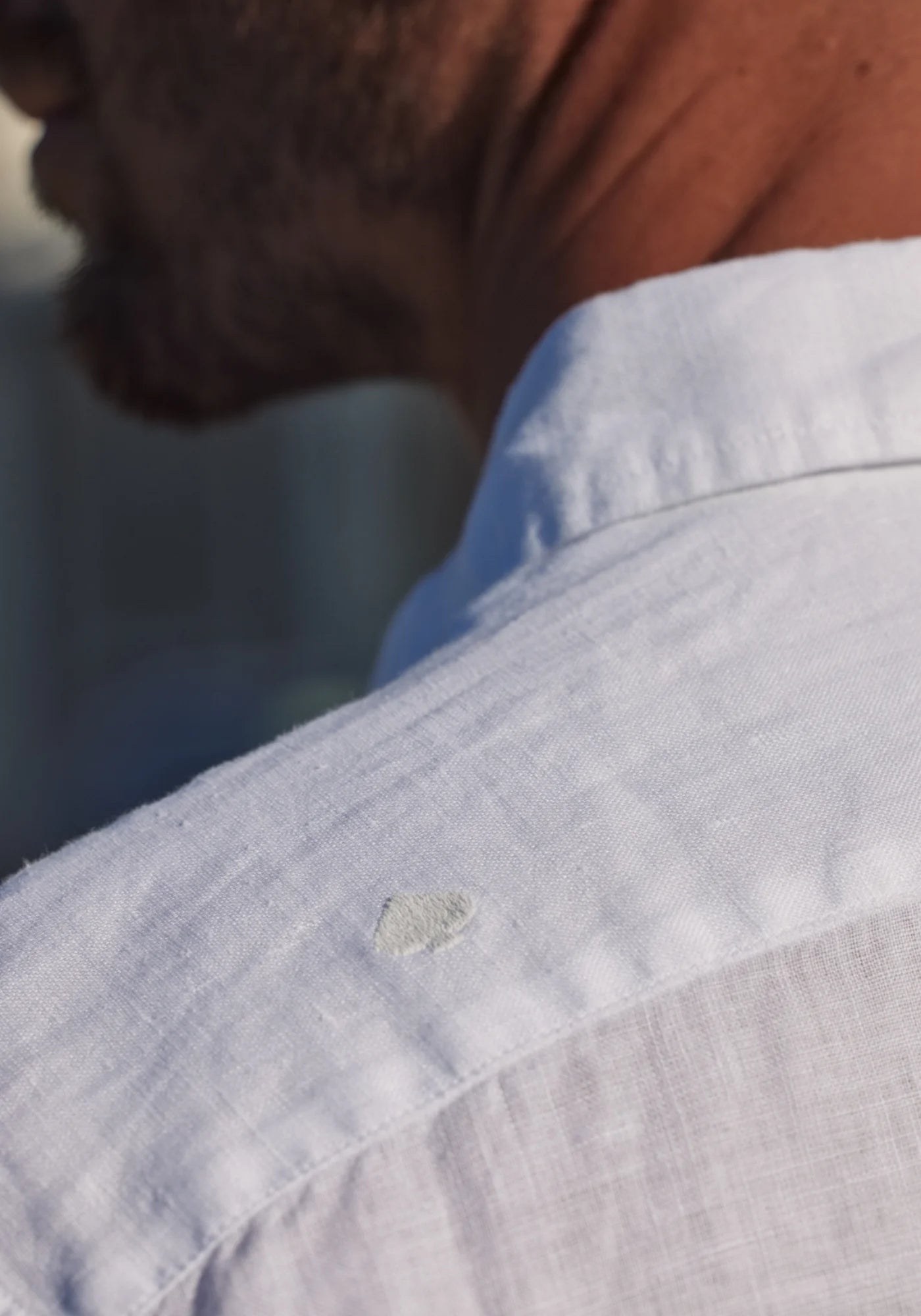 Zoom sur le logo Jaqk brodé à l'arrière de la chemise en lin Bali blanche que l'homme porte