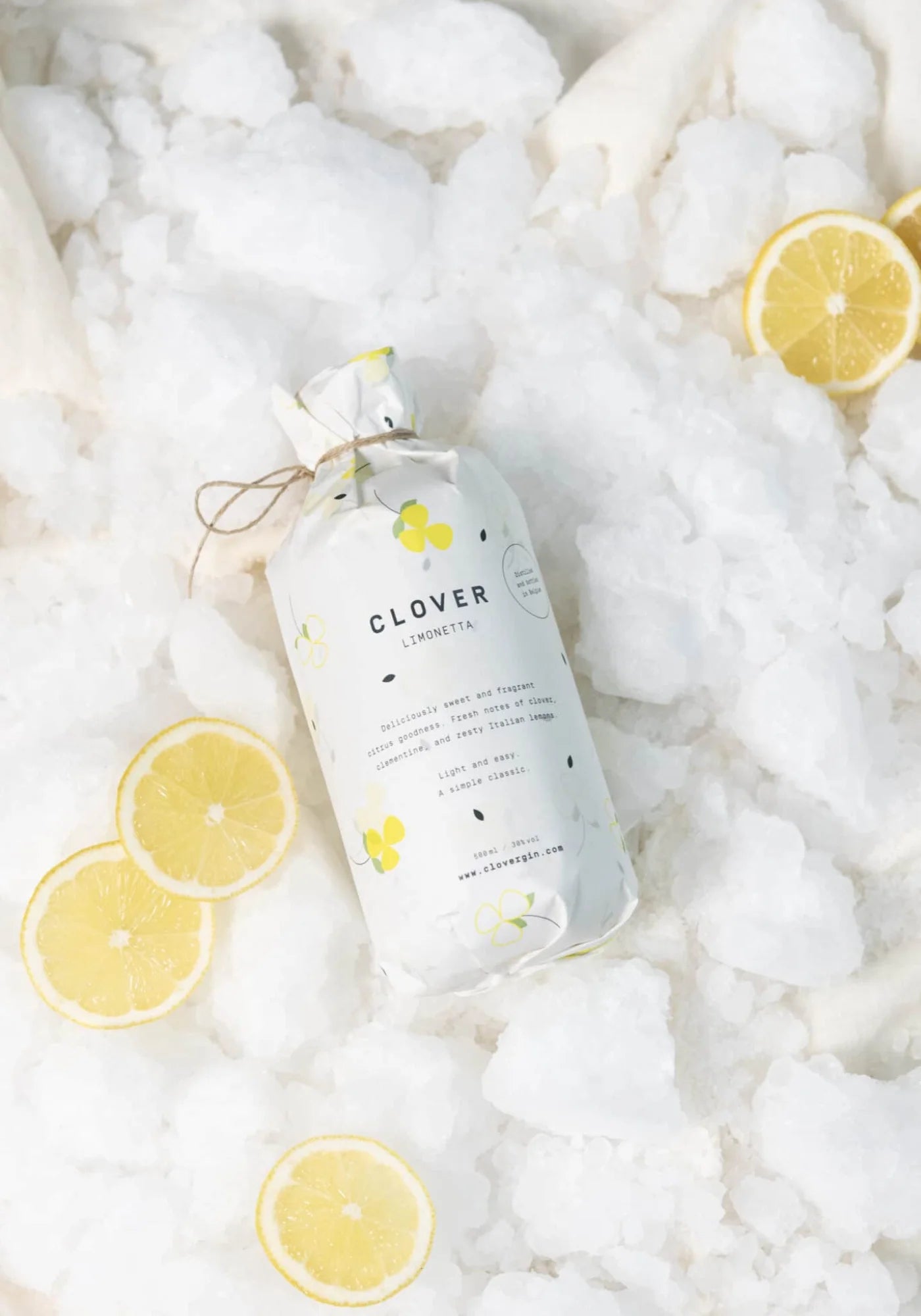 Le Clover Limonetta de chez Clover Gin emballé, posé sur de la glace et entouré de citrons