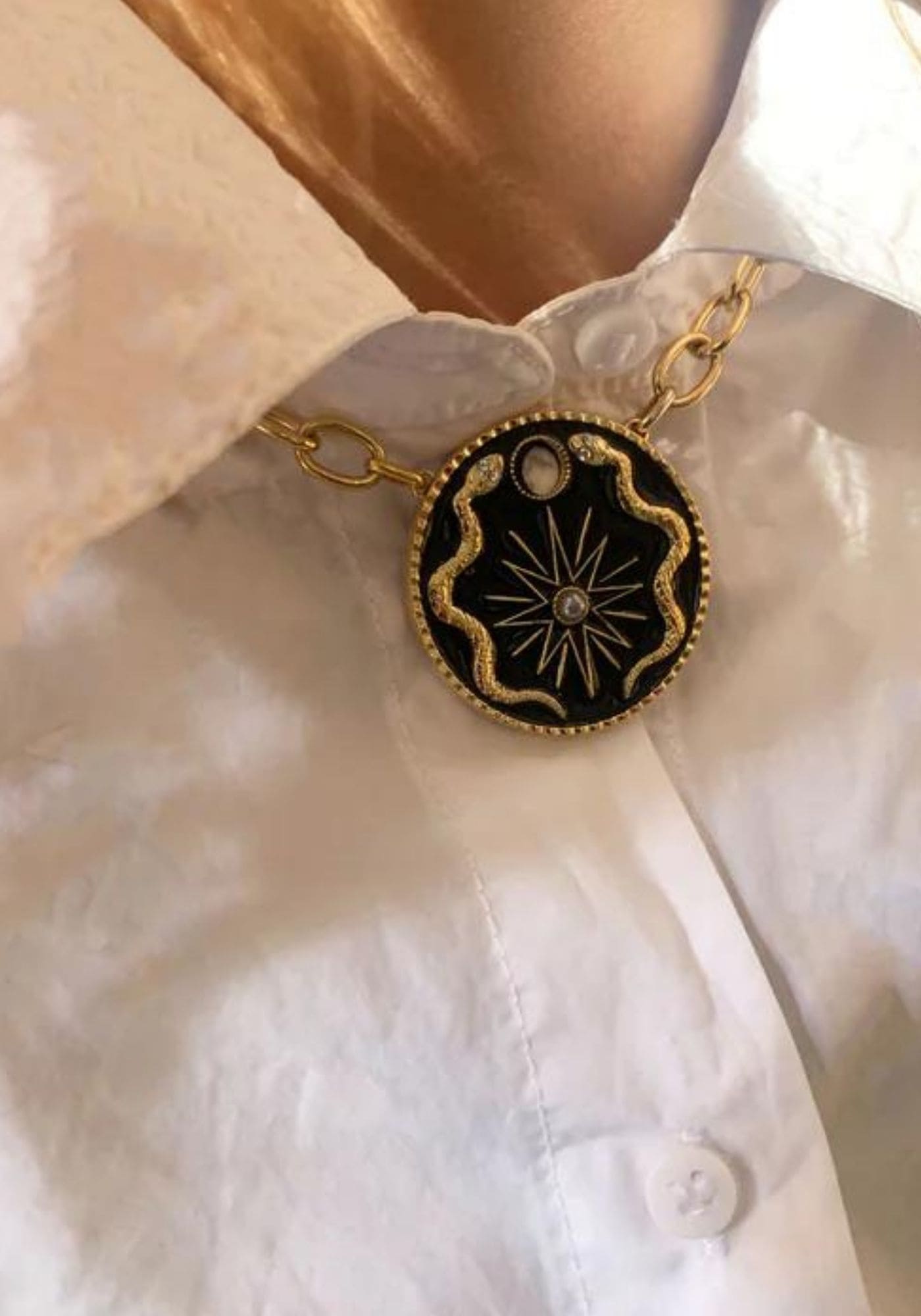La femme porte le collier The Moon Cycle Wheel en noir de chez Maison 77 sur une chemise blanche
