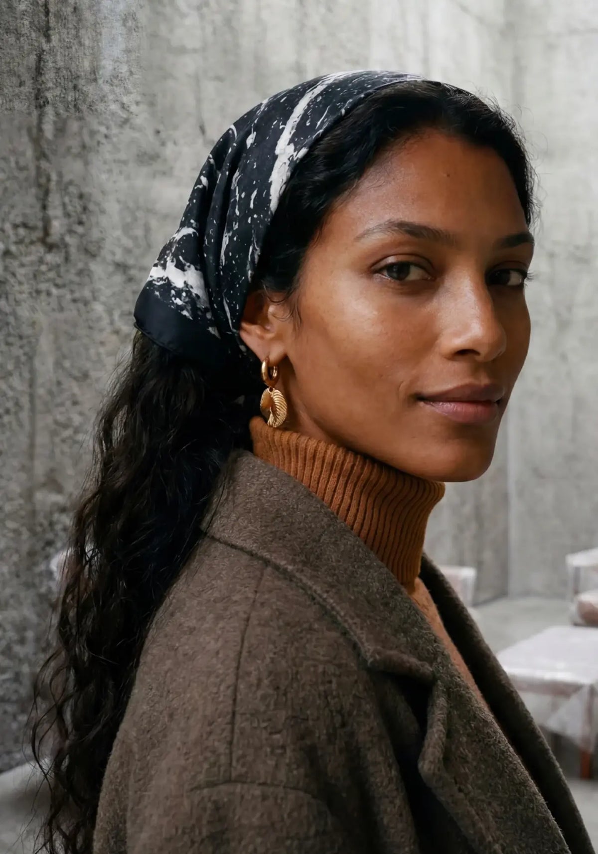 La femme porte le foulard granit obsidienne noir de chez Antan Créations
