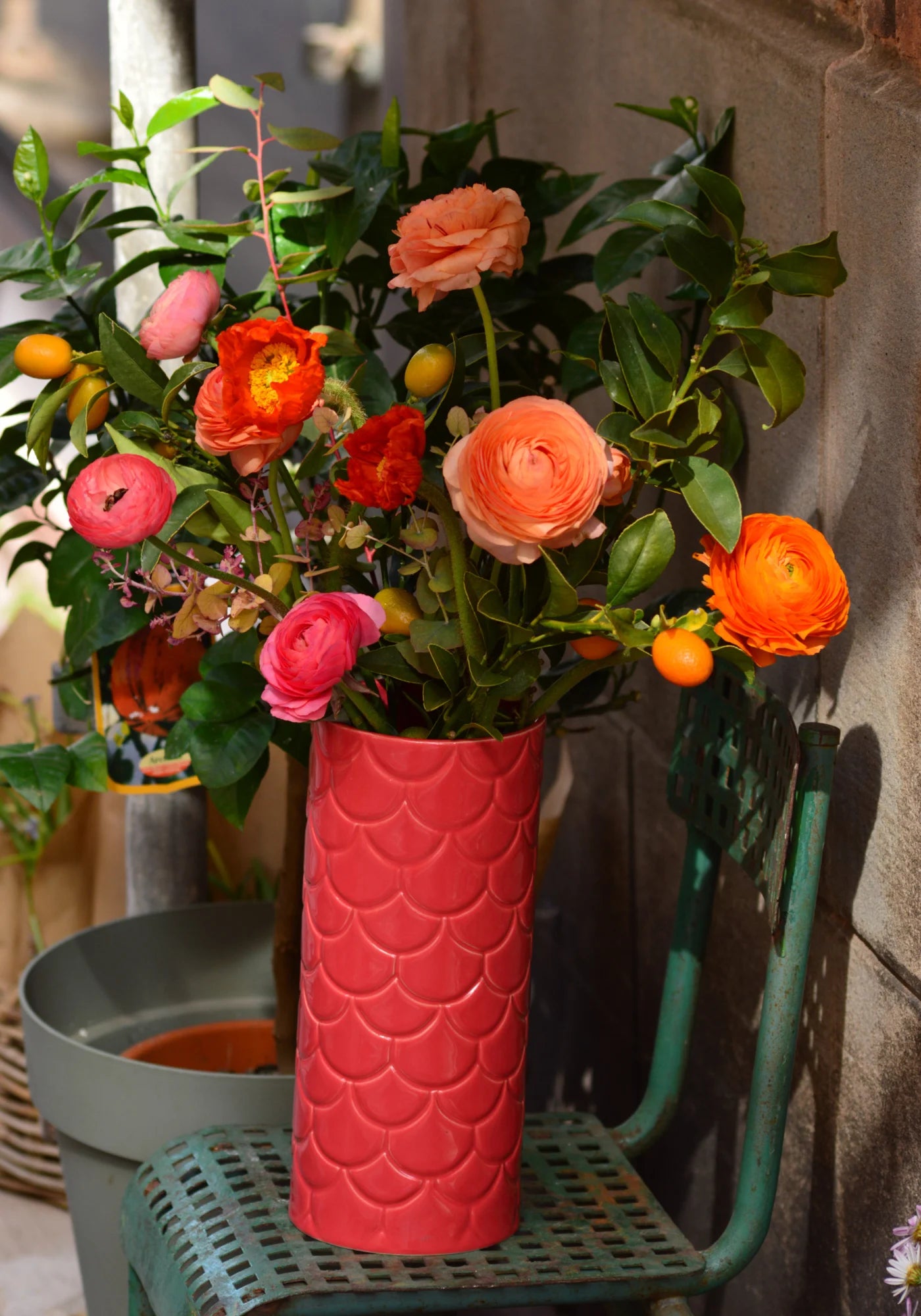 Le grand vase en Grès rose de chez Maison Marah rempli d'un bouquet de fleurs et posé sur une chaise