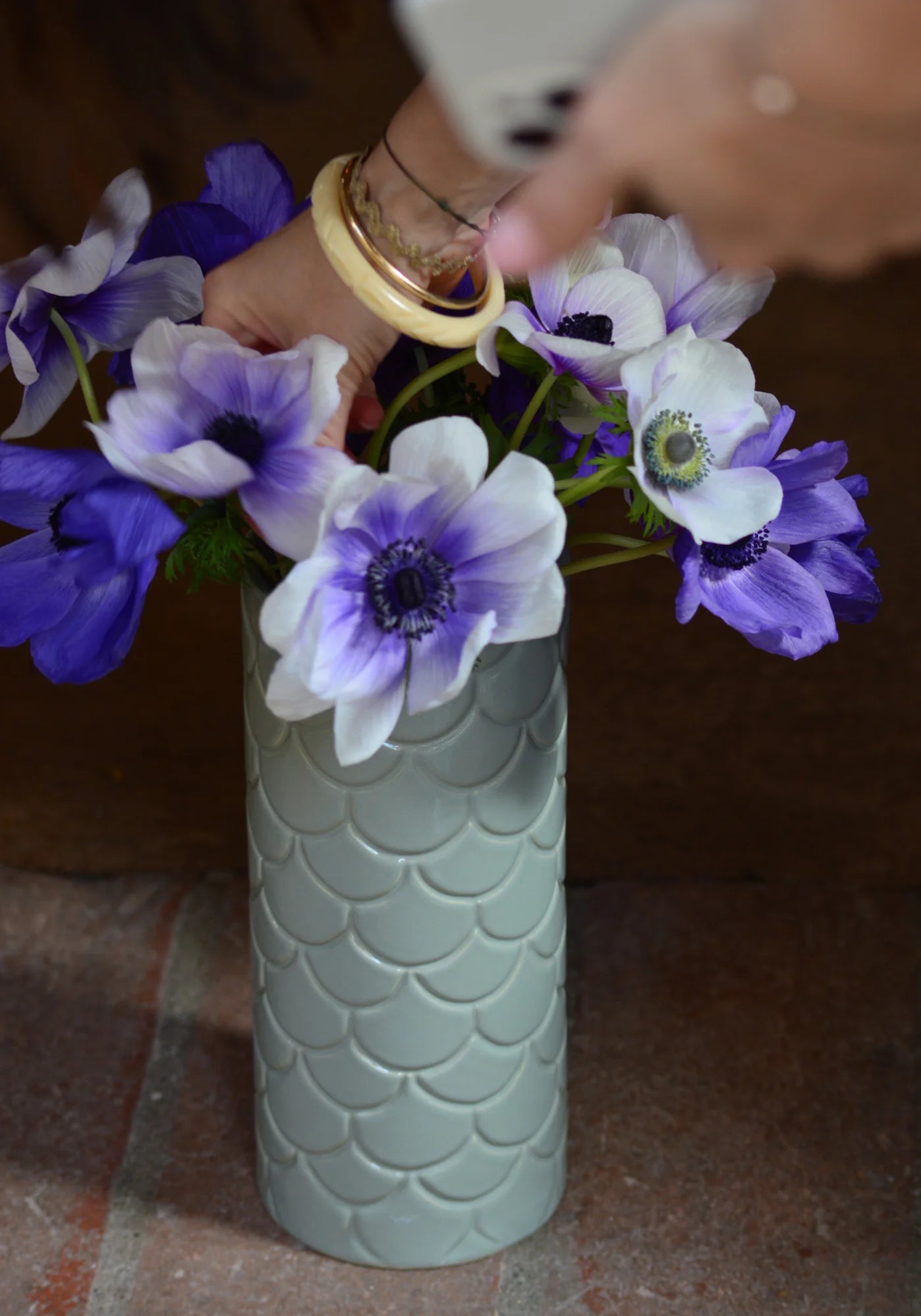 La femme rempli le grand vase en Grès vert de chez Maison Marah de fleurs