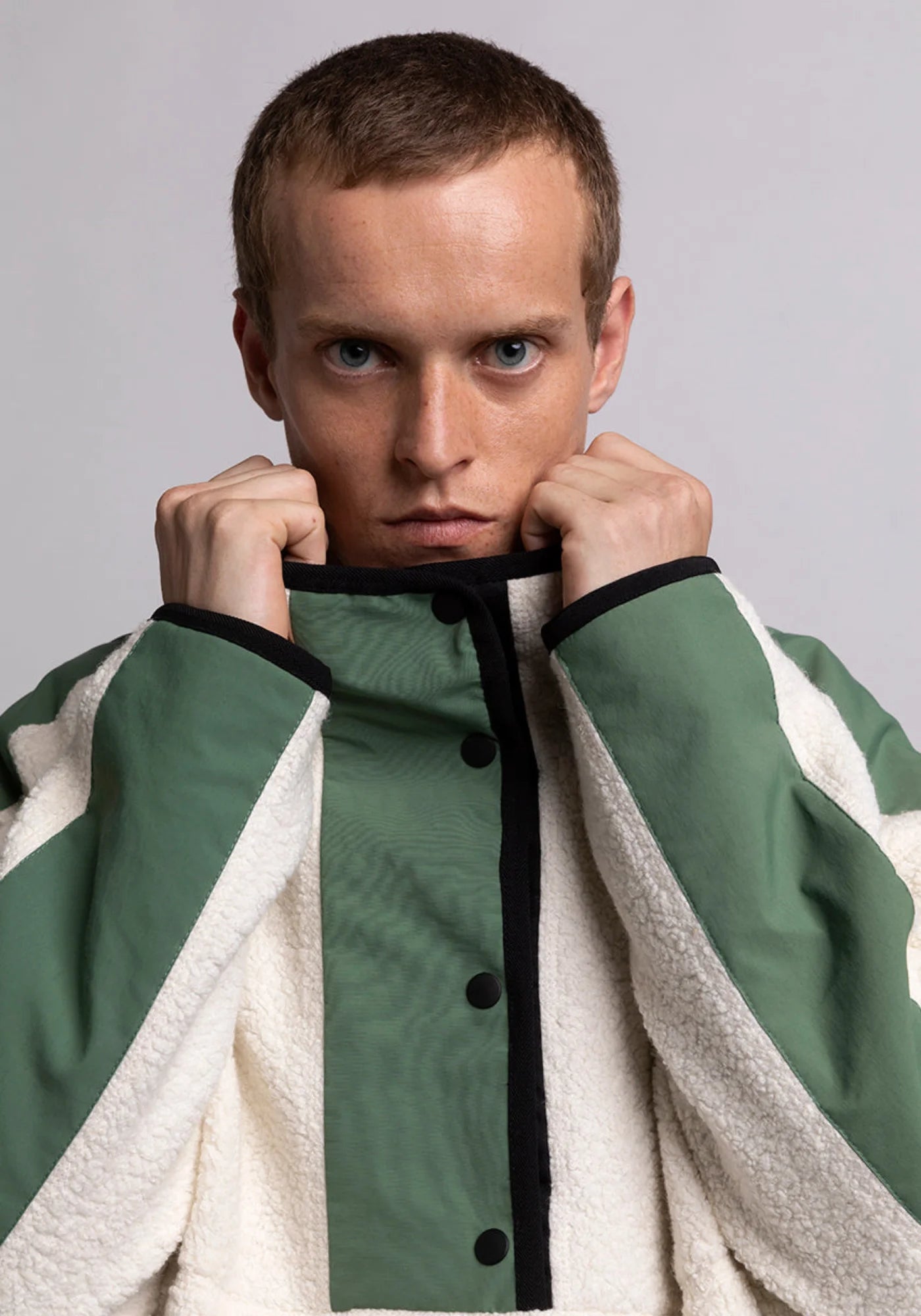 Zoom sur l'homme qui porte le hoodie Sherpa unisexe Cocoon écrue et vert de chez Mout Mout