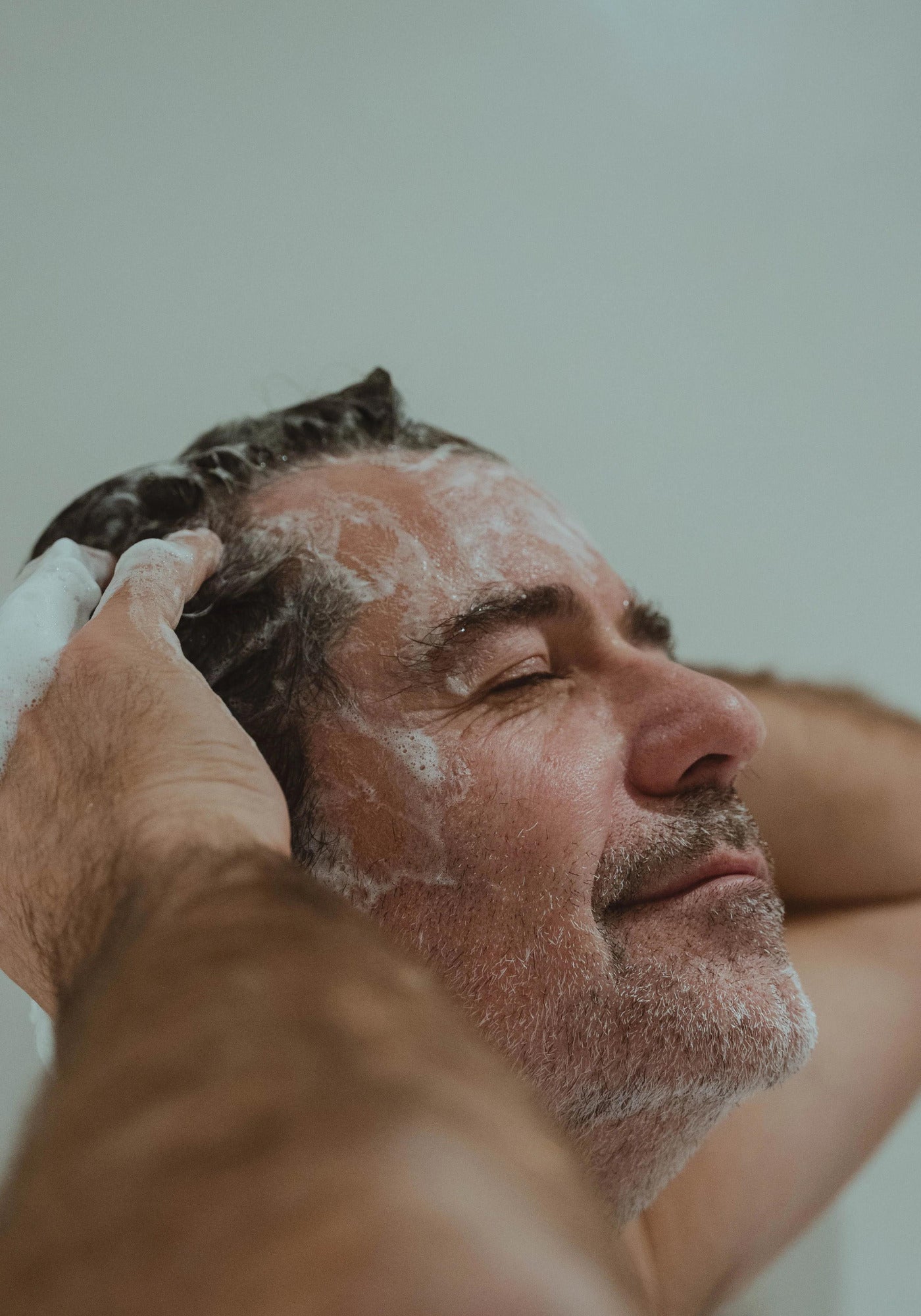 L'homme se lave les cheveux avec le gel douche corps et cheveux sublime de chez Atlantik Care