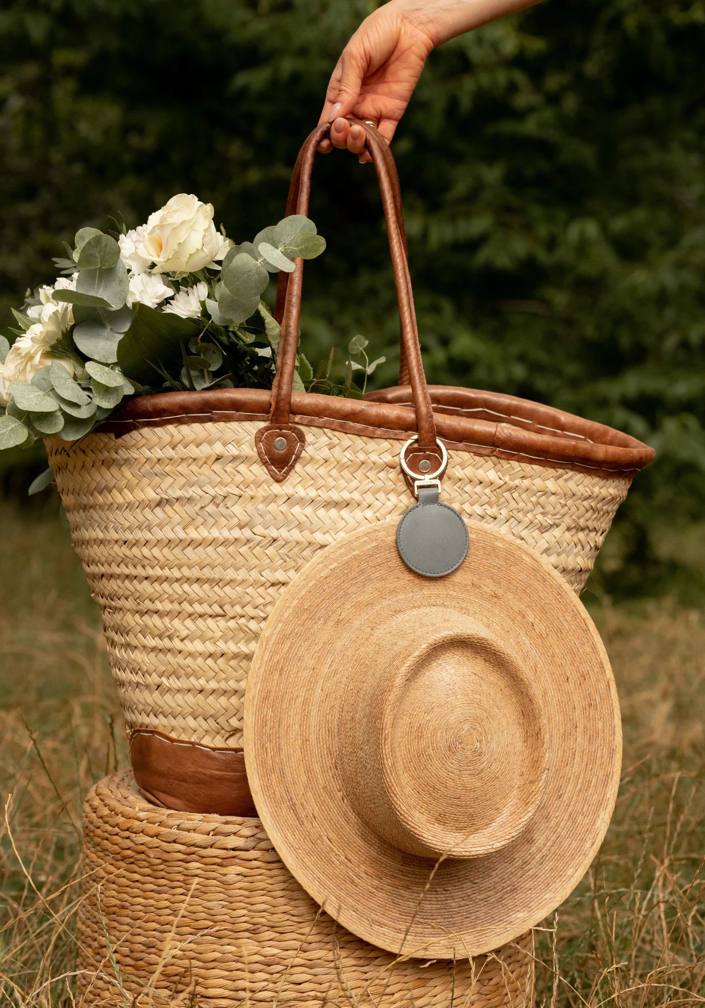 La pince à chapeau Sun gris de chez Palma B accrochée à un panier et à un chapeau de paille